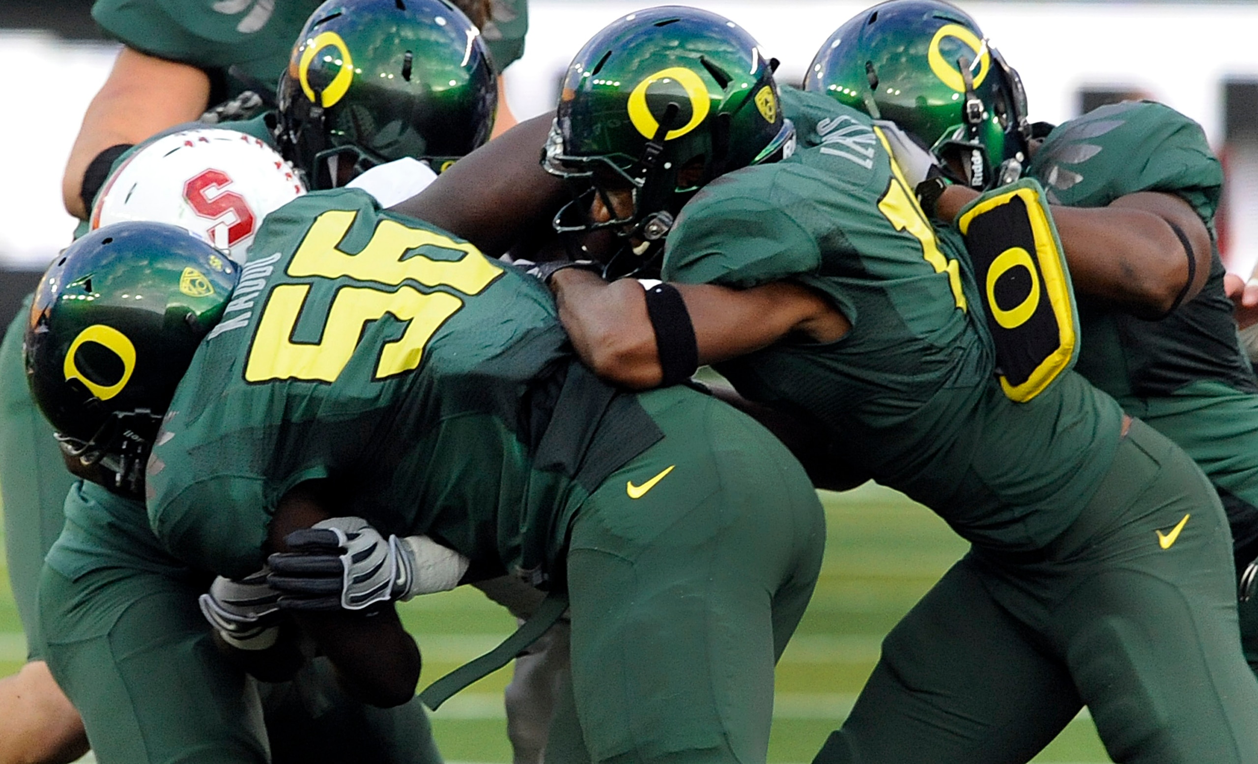 EUGENE, OR - OCTOBER 2: Linebacker Josh Kaddu #56 and safety Javes Lewis #14 of the Oregon Ducks team up to tackle running back Stepfan Taylor #33 of the Stanford Cardinal in the second quarter of the game at Autzen Stadium on October 2, 2010 in Eugene, O