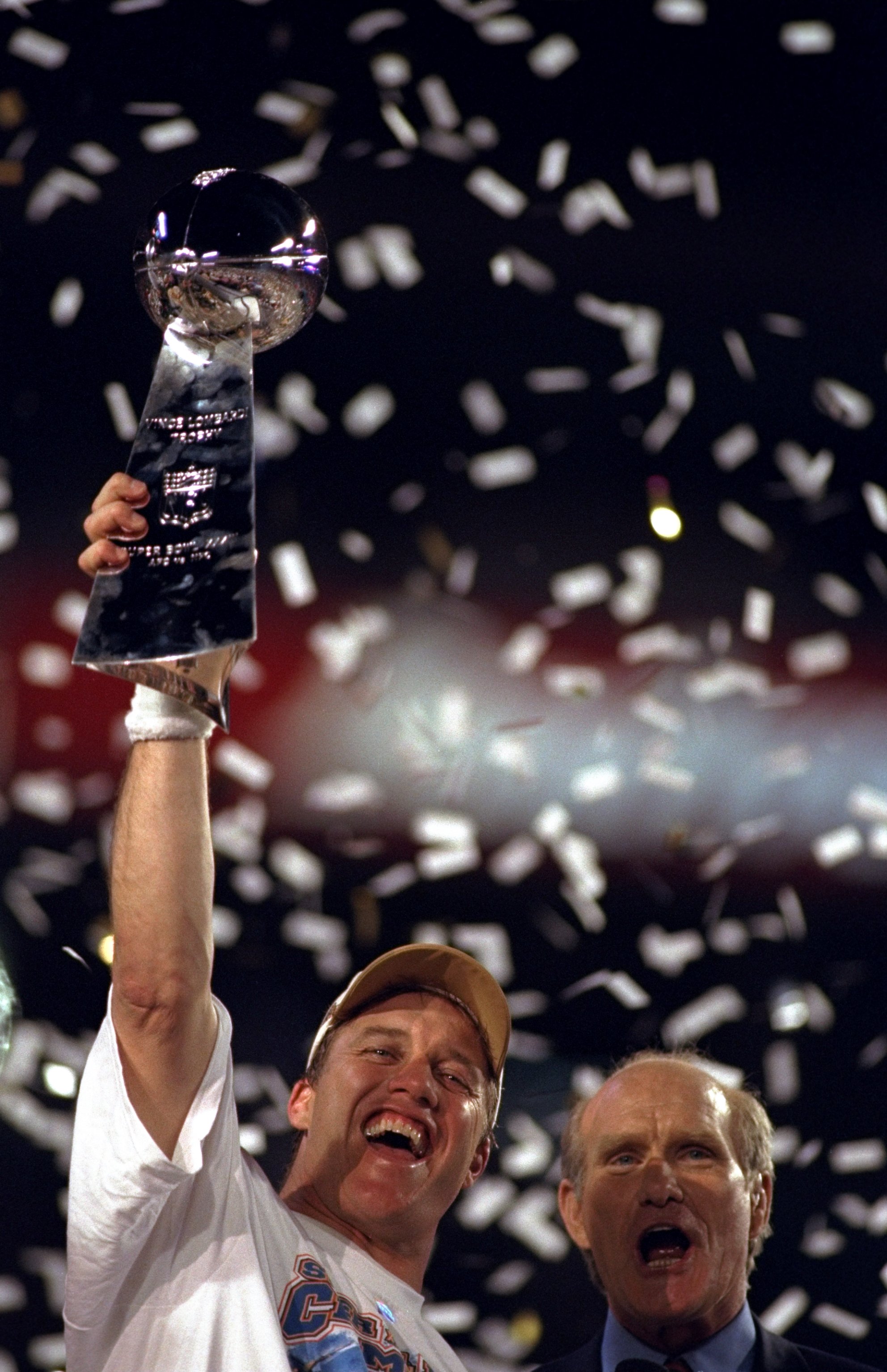 31 Jan 1999: Fox Sports TV analyst Terry Bradshaw cheers as confetti rains down on quarterback John Elway #7 of the Denver Broncos as he lifts the Vince Lombardi Trophy after defeating the Atlanta Falcons to win Super Bowl XXXIII at Pro Player Stadium in