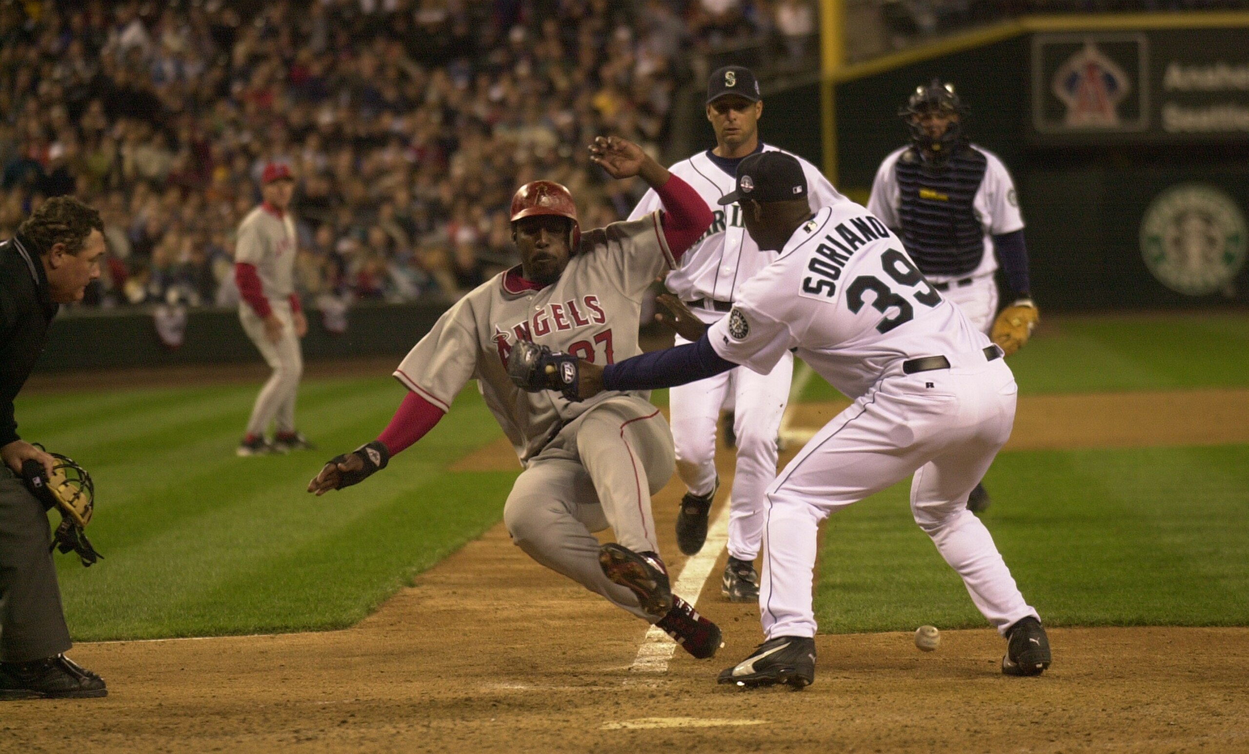 SEATTLE - APRIL 7:  Vladimir Guerrero #27 of the Anaheim Angels scores when Rafael Soriano #39 of the Seattle Mariners drops the ball on April 7 2004 at Safeco Field in Seattle, Washington. Soriano was charged with an error on the play.  (Photo by Otto Gr