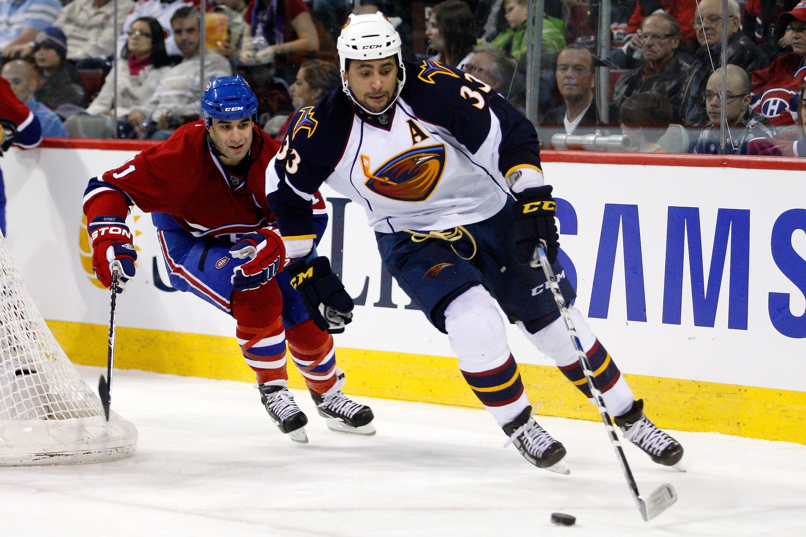 MONTREAL, CANADA - JANUARY 2:  Dustin Byfuglien #33 of the Atlanta Thrashers skates with the puck while being chased by Scott Gomez #11 of the Montreal Canadiens during the NHL game at the Bell Centre on January 2, 2011 in Montreal, Quebec, Canada.  The T