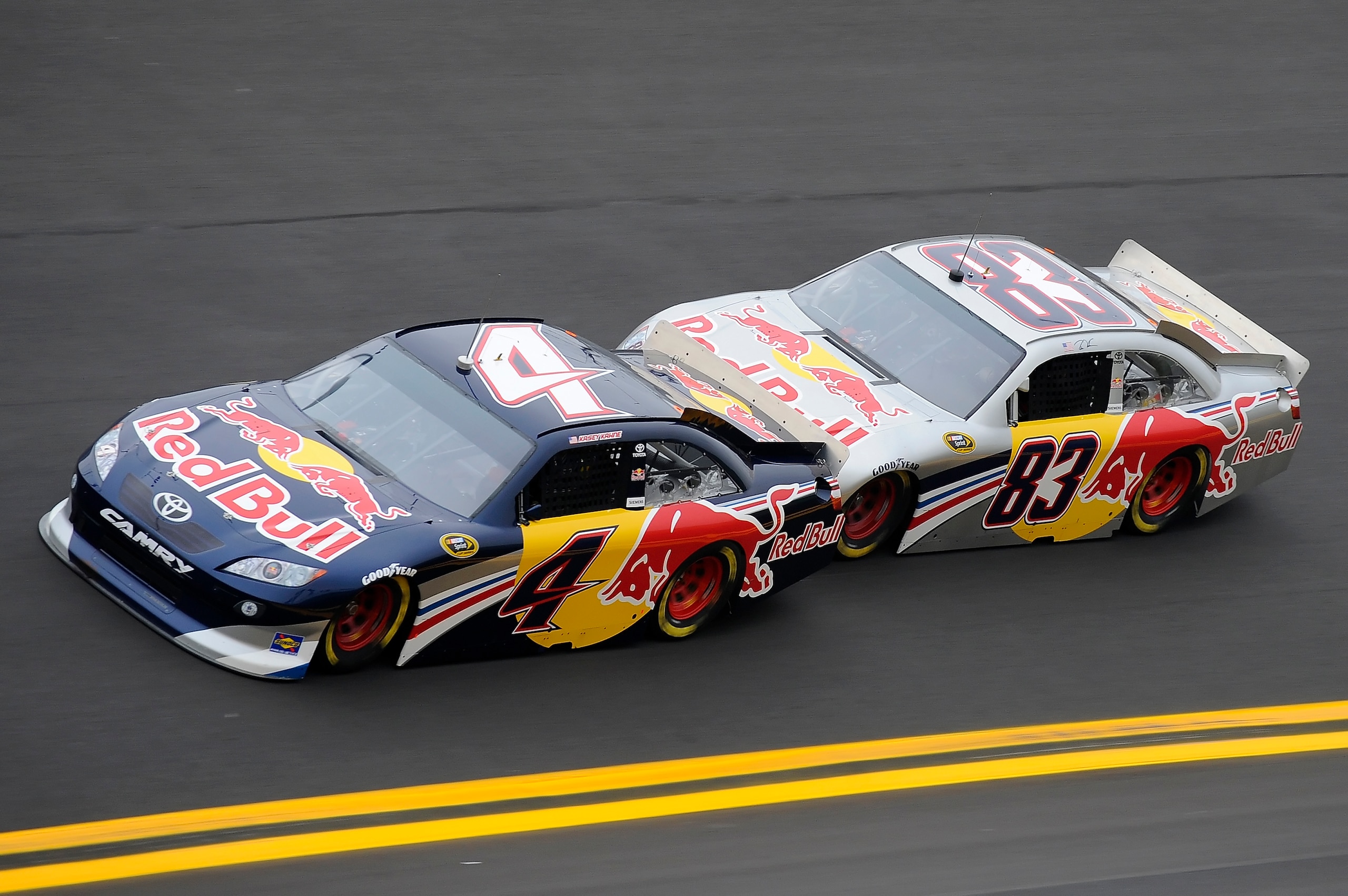 DAYTONA BEACH, FL - JANUARY 21:  Brian Vickers, driver of the #83 Red Bull Toyota, pushes teammate Kasey Kahne, driver of the #4 Red Bull Toyota, through turn four during testing at Daytona International Speedway on January 21, 2011 in Daytona Beach, Flor