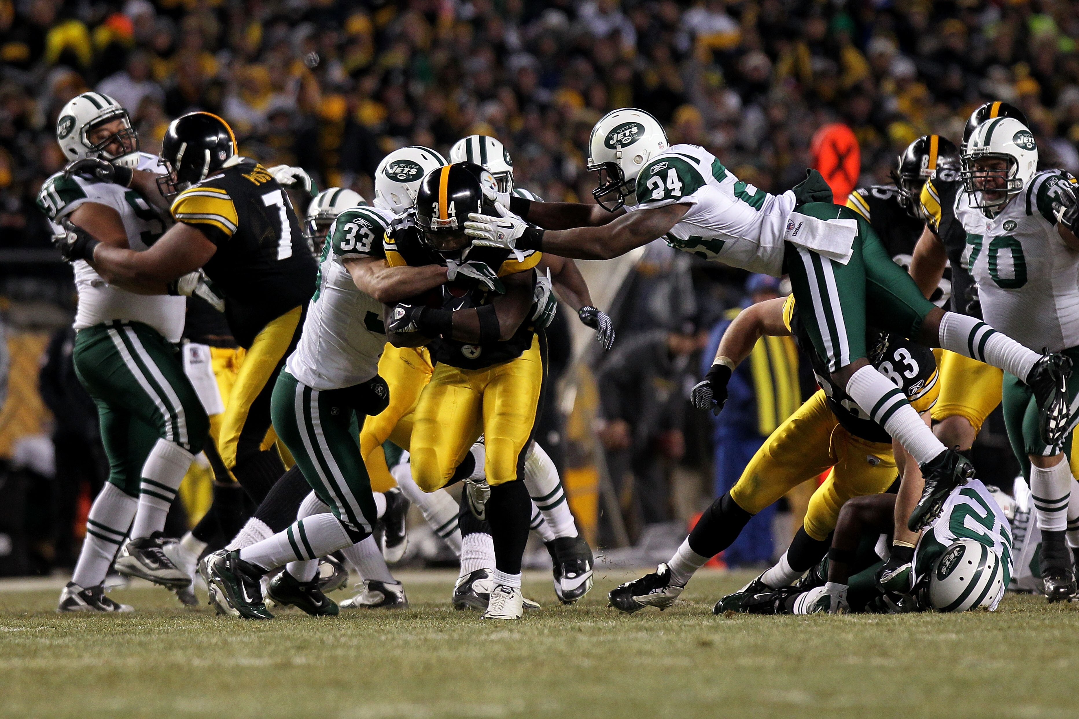 PITTSBURGH, PA - JANUARY 23:  Rashard Mendenhall #34 of the Pittsburgh Steelers tries to avoid the tackle of James Ihedigbo #44 and Darrelle Revis #24 of the New York Jets during the 2011 AFC Championship game at Heinz Field on January 23, 2011 in Pittsbu