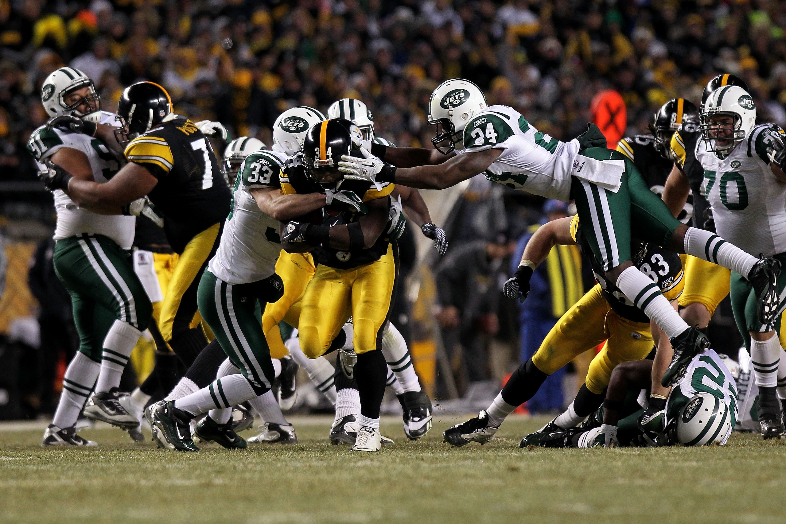 PITTSBURGH, PA - JANUARY 23:  Rashard Mendenhall #34 of the Pittsburgh Steelers tries to avoid the tackle of James Ihedigbo #44 and Darrelle Revis #24 of the New York Jets during the 2011 AFC Championship game at Heinz Field on January 23, 2011 in Pittsbu