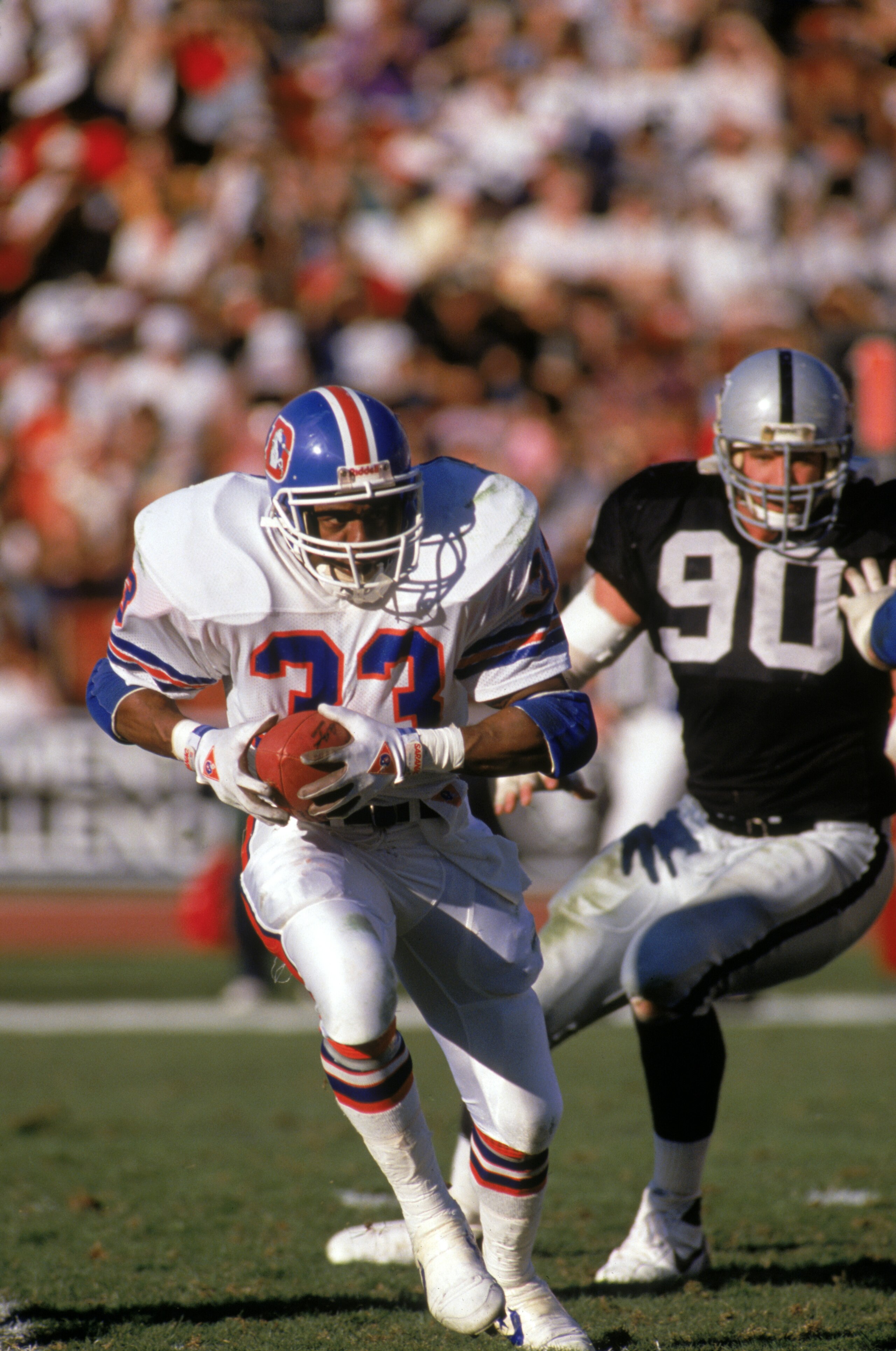LOS ANGELES - DECEMBER 4: Running back Tony Dorsett #33 of the Denver Broncos runs away from defensive end Mike Wise #90 of the Los Angeles Raiders during a game at the Los Angeles Memorial Coliseum on December 4, 1988 in Los Angeles, California. The Ra LOS ANGELES - DECEMBER 4: Running back Tony Dorsett #33 of the Denver Broncos runs away from defensive end Mike Wise #90 of the Los Angeles Raiders during a game at the Los Angeles Memorial Coliseum on December 4, 1988 in Los Angeles, California. The Ra