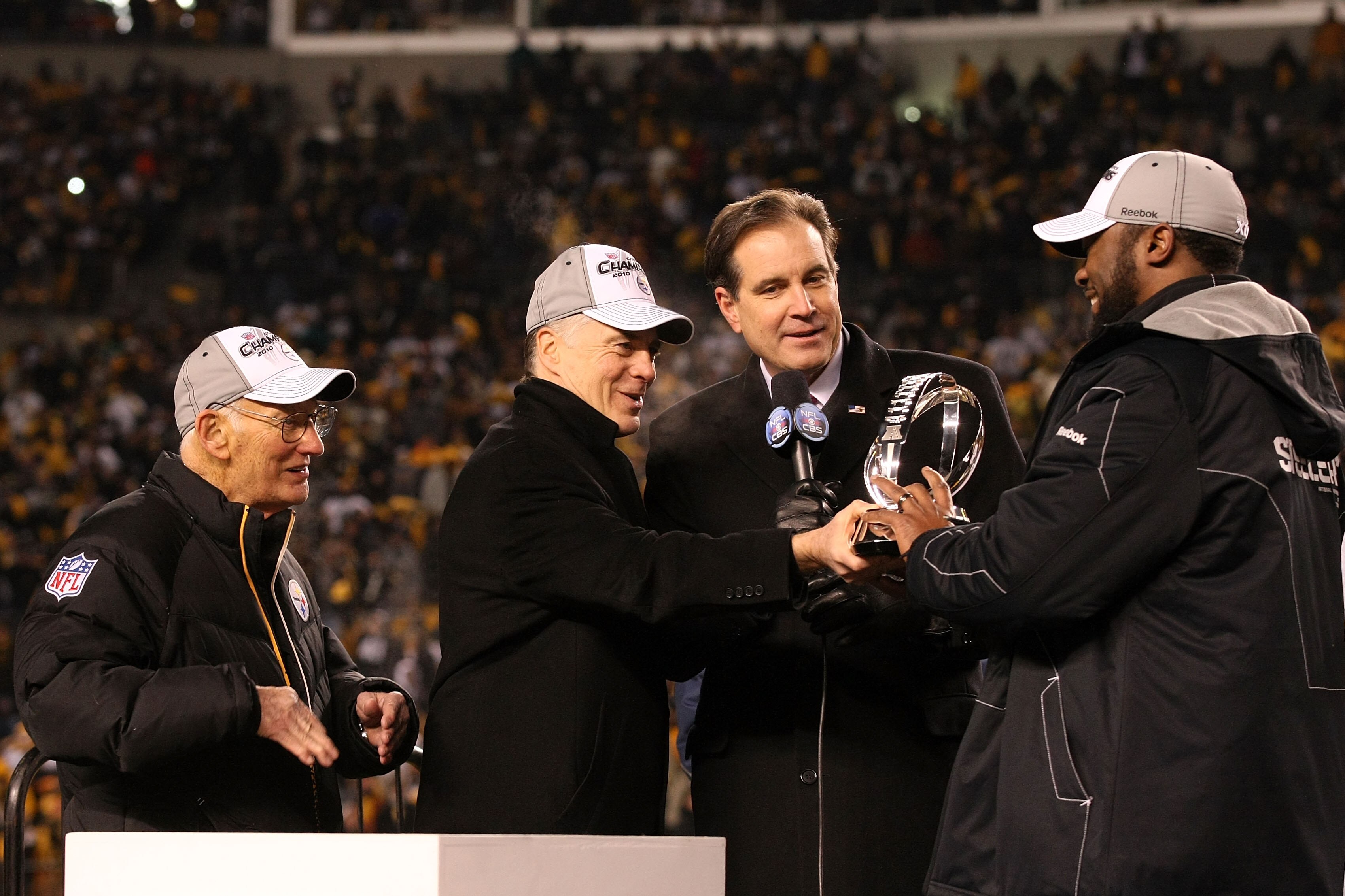 PITTSBURGH, PA - JANUARY 23:  Owner Dan Rooney (L), Team president Art Rooney II (2ndL),  and head coach Mike Tomlin (R) of the Pittsburgh Steelers recieve the Lamar Hunt Trophy as CBS sportscaster Jim Nantz looks on after their 24 to 19 win over the New