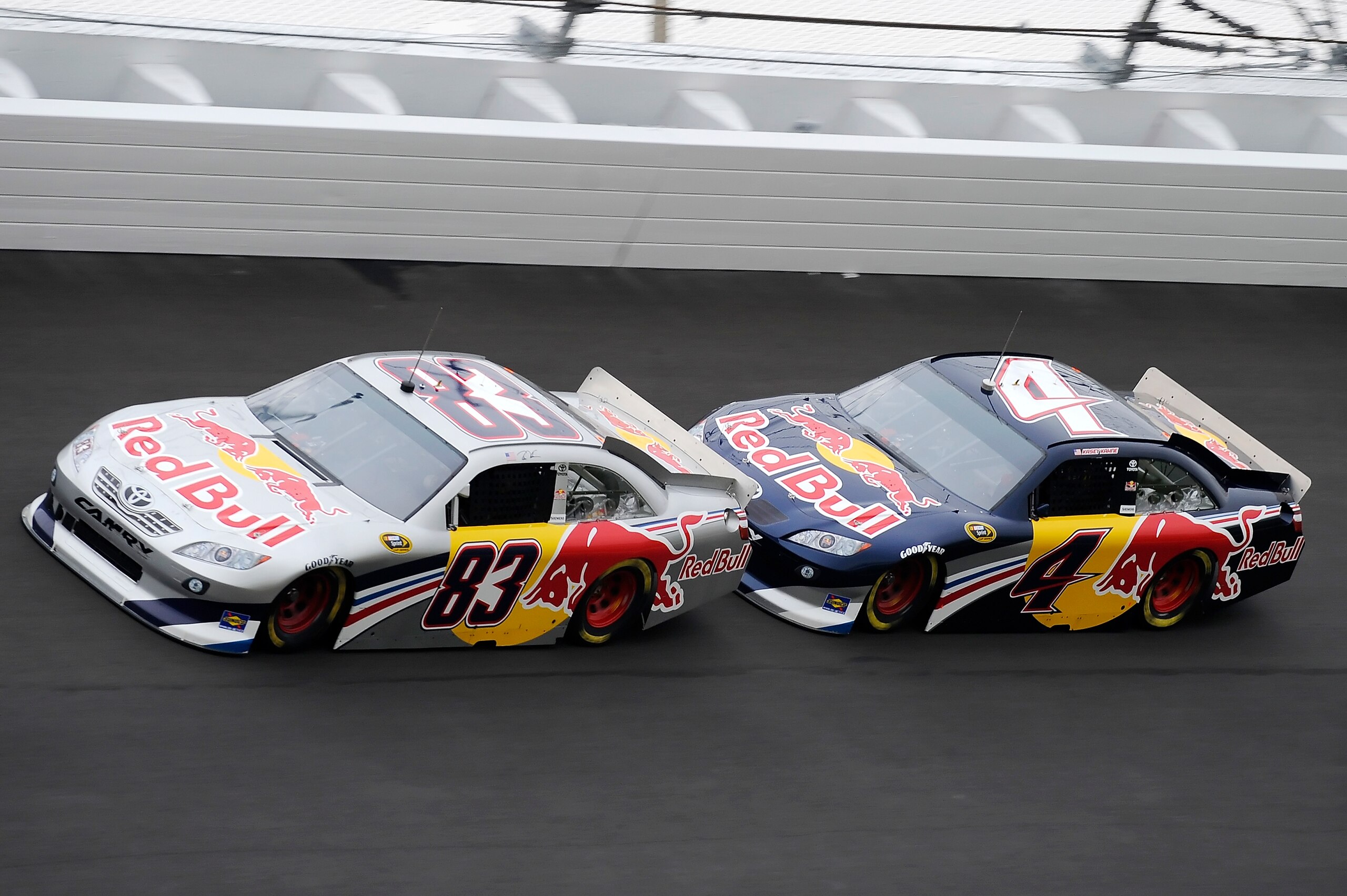 DAYTONA BEACH, FL - JANUARY 21:  Brian Vickers, driver of the #83 Red Bull Toyota, gets a push from teammate Kasey Kahne, driver of the #4 Red Bull Toyota, exiting turn four during testing at Daytona International Speedway on January 21, 2011 in Daytona B