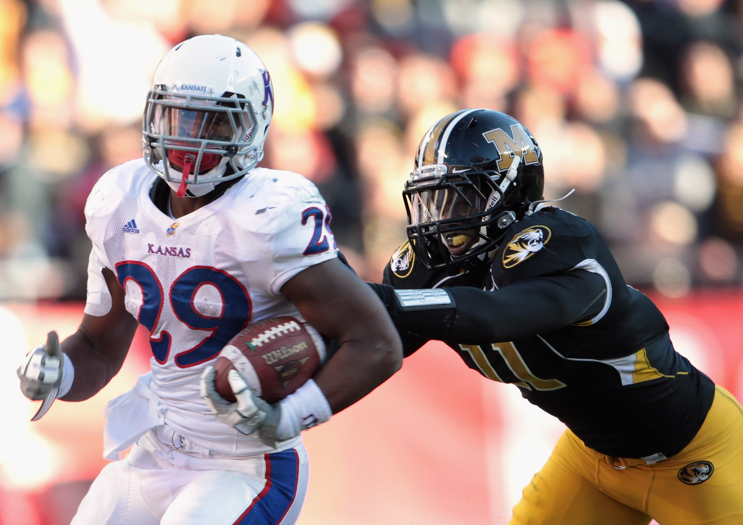 KANSAS CITY, MO - NOVEMBER 27: James Sims #29 of the Kansas Jayhawks carries the ball as Jarrell Harrison #11 of the Missouri Tigers defends during the game on November 27, 2010 at Arrowhead Stadium in Kansas City, Missouri. (Photo by Jamie Squire/Getty