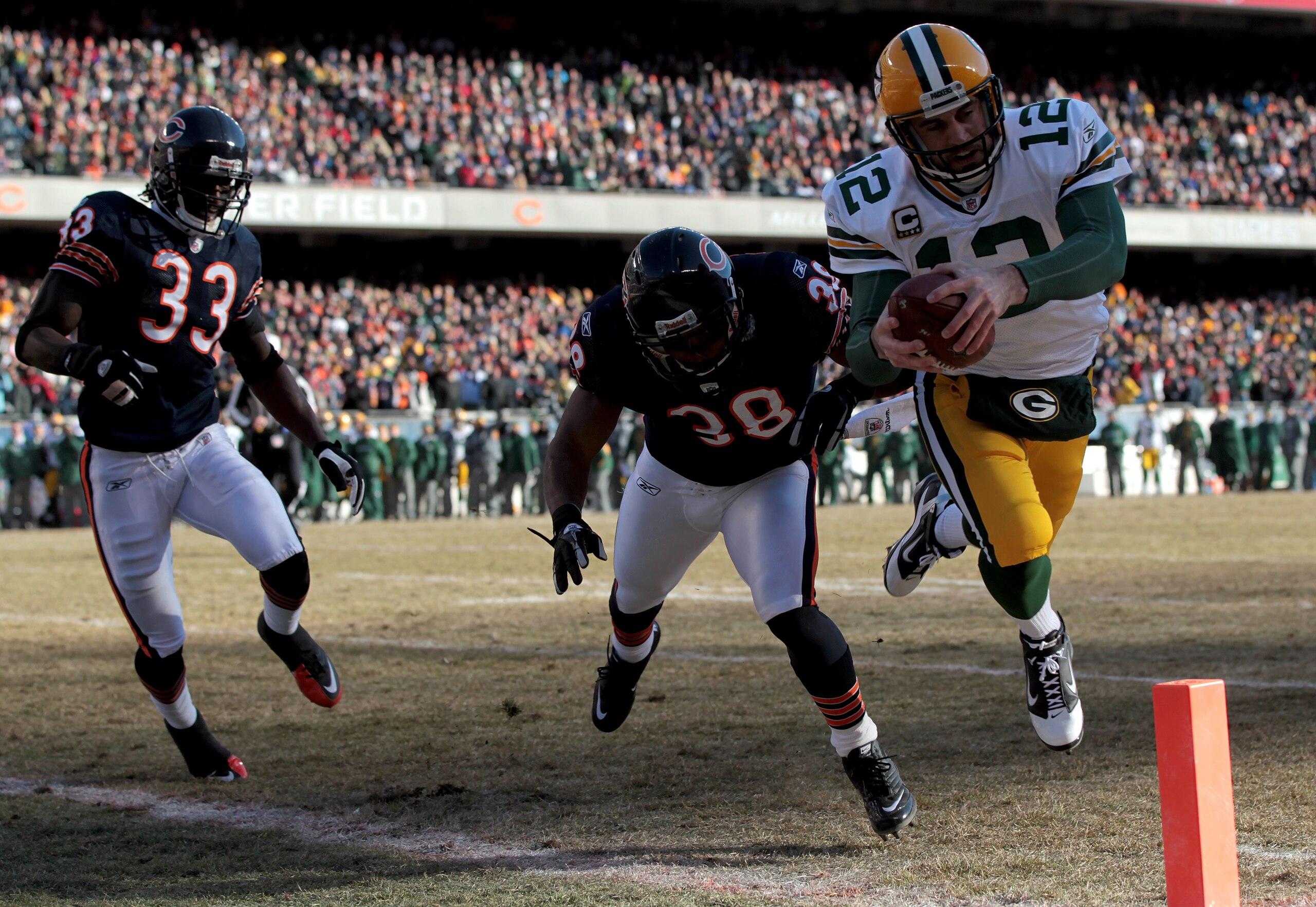 CHICAGO, IL - JANUARY 23: Quarterback Aaron Rodgers #12 of the Green Bay Packers dives into the corner of the endzone for a one-yard touchdown run against Danieal Manning #38 of the Chicago Bears in the first quarter of the NFC Championship Game at Soldi CHICAGO, IL - JANUARY 23: Quarterback Aaron Rodgers #12 of the Green Bay Packers dives into the corner of the endzone for a one-yard touchdown run against Danieal Manning #38 of the Chicago Bears in the first quarter of the NFC Championship Game at Soldi