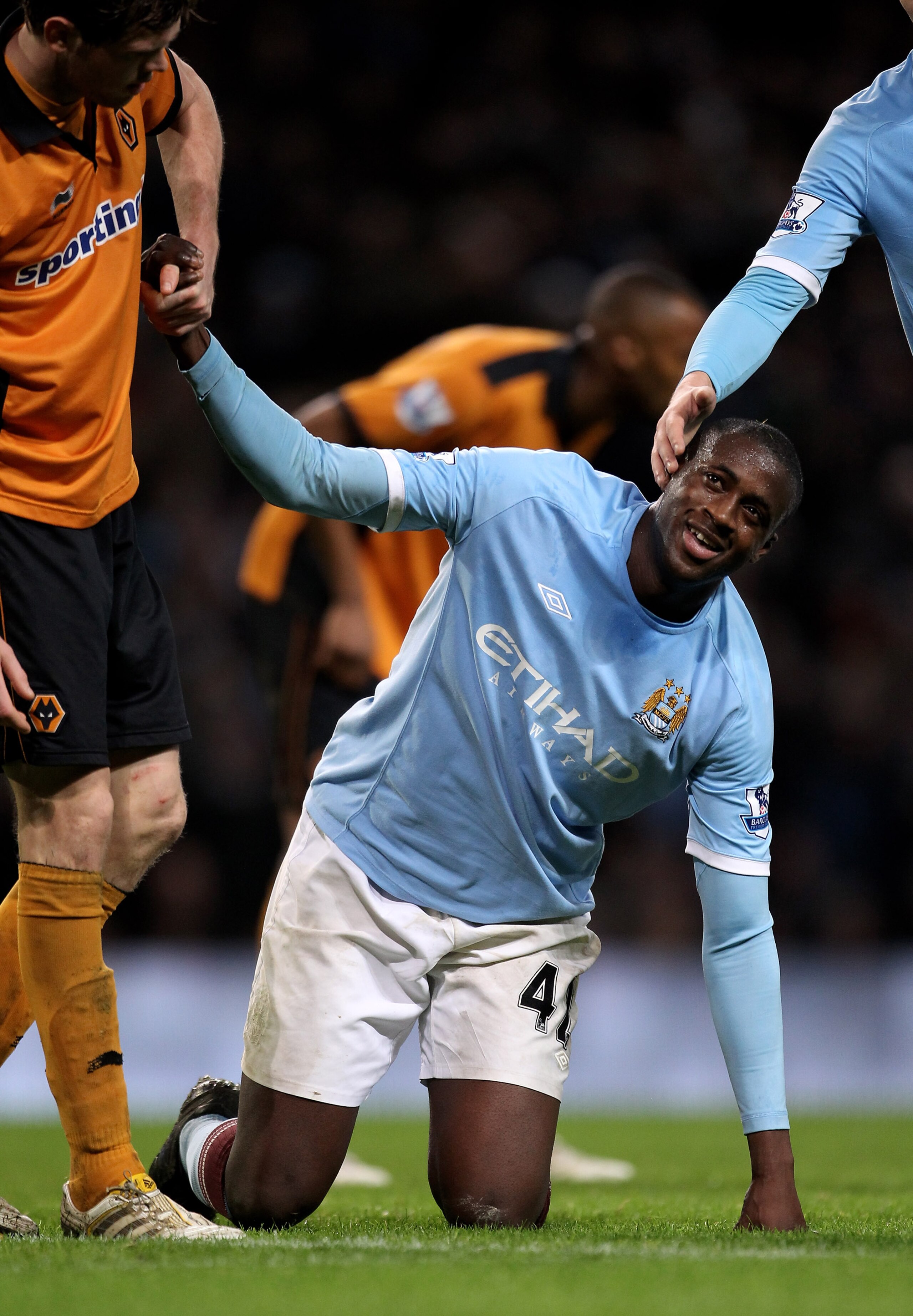 MANCHESTER, ENGLAND - JANUARY 15:   Yaya Toure of Manchester City is helped to his feet during the Barclays Premier League match between Manchester City and Wolverhampton Wanderers at the City of Manchester Stadium on January 15, 2011 in Manchester, Engla
