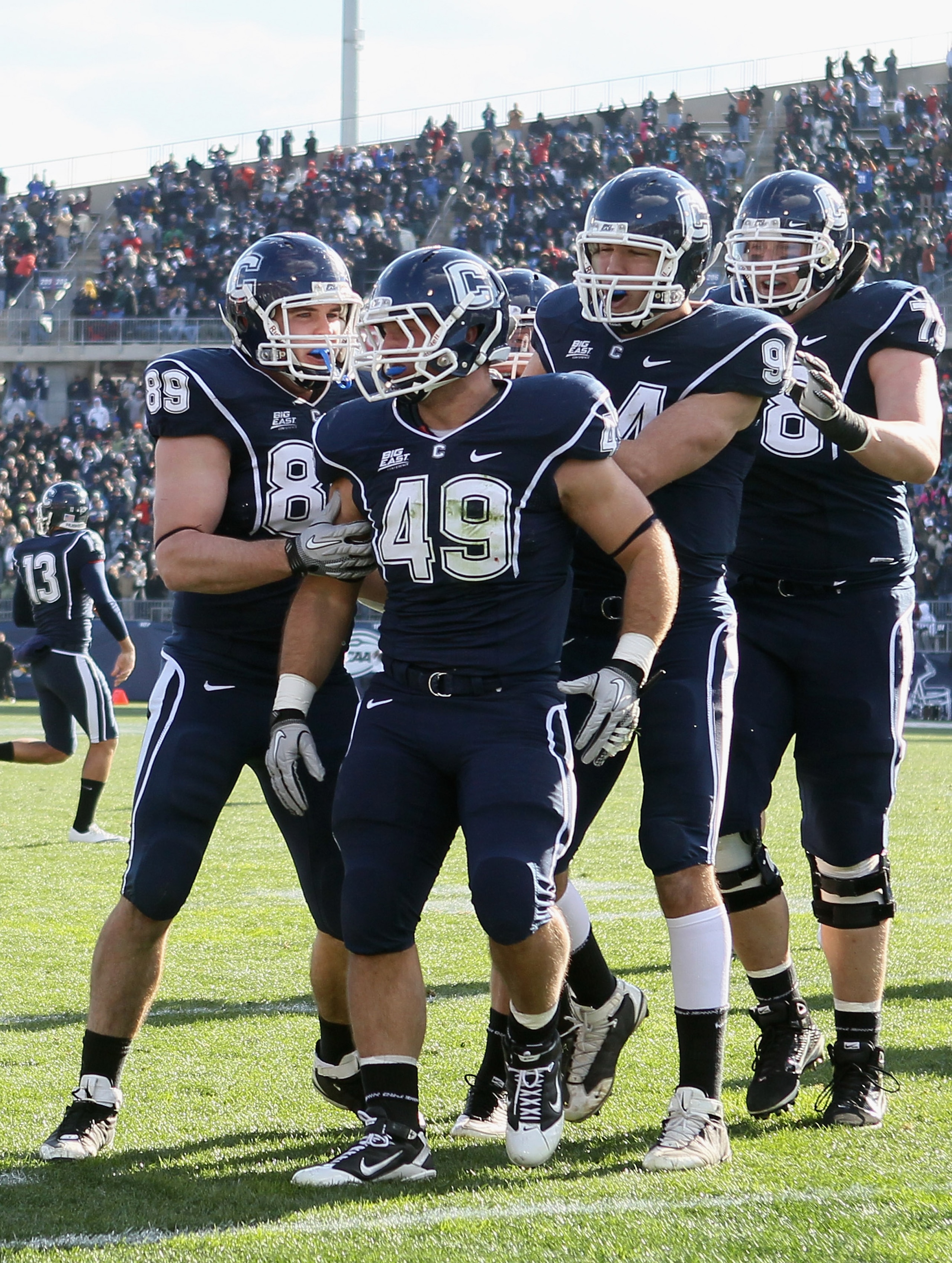 EAST HARTFORD, CT - NOVEMBER 27:  Anthony Sherman #49 of the Connecticut Huskies is congratulated by teammates John Delahunt #89 and Ryan Griffin #94 after Sherman scored a touchdown in the first quarter against Cincinnati Bearcats defends on November 27,