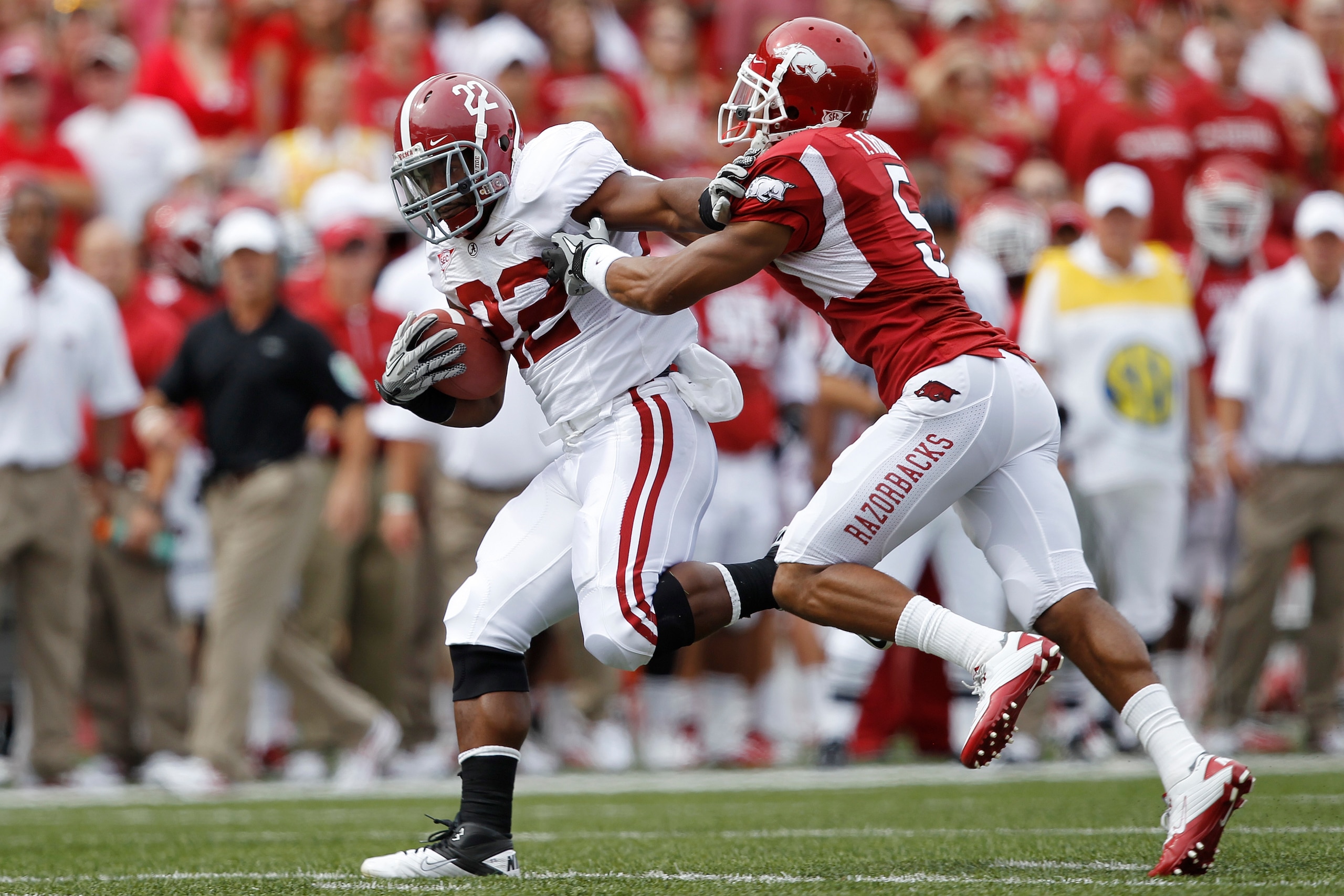 FAYETTEVILLE - SEPTEMBER 25: Mark Ingram #22 of the Alabama Crimson Tide pushes away a tackle attempt by Tramain Thomas #5 of the Arkansas Razorbacks during a first half touchdown run at Donald W. Reynolds Razorback Stadium on September 25, 2010 in Fayett