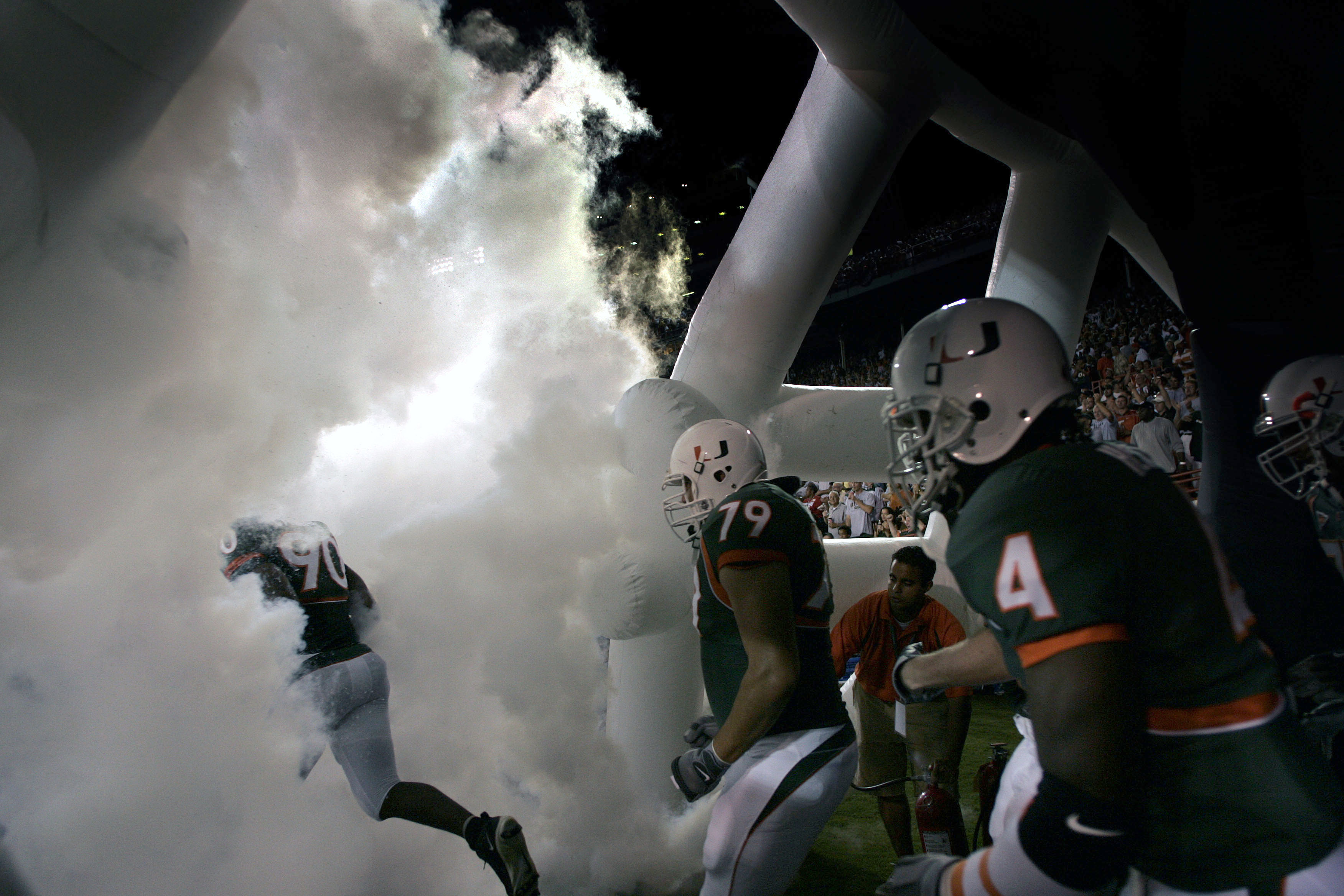 MIAMI - OCTOBER 14:  University of Miami football players run through smoke before the start of their game against the University of Louisville on October 14, 2004 at the Orange Bowl in Miami, Florida.  (Photo by Eliot J. Schechter/Getty Images)
