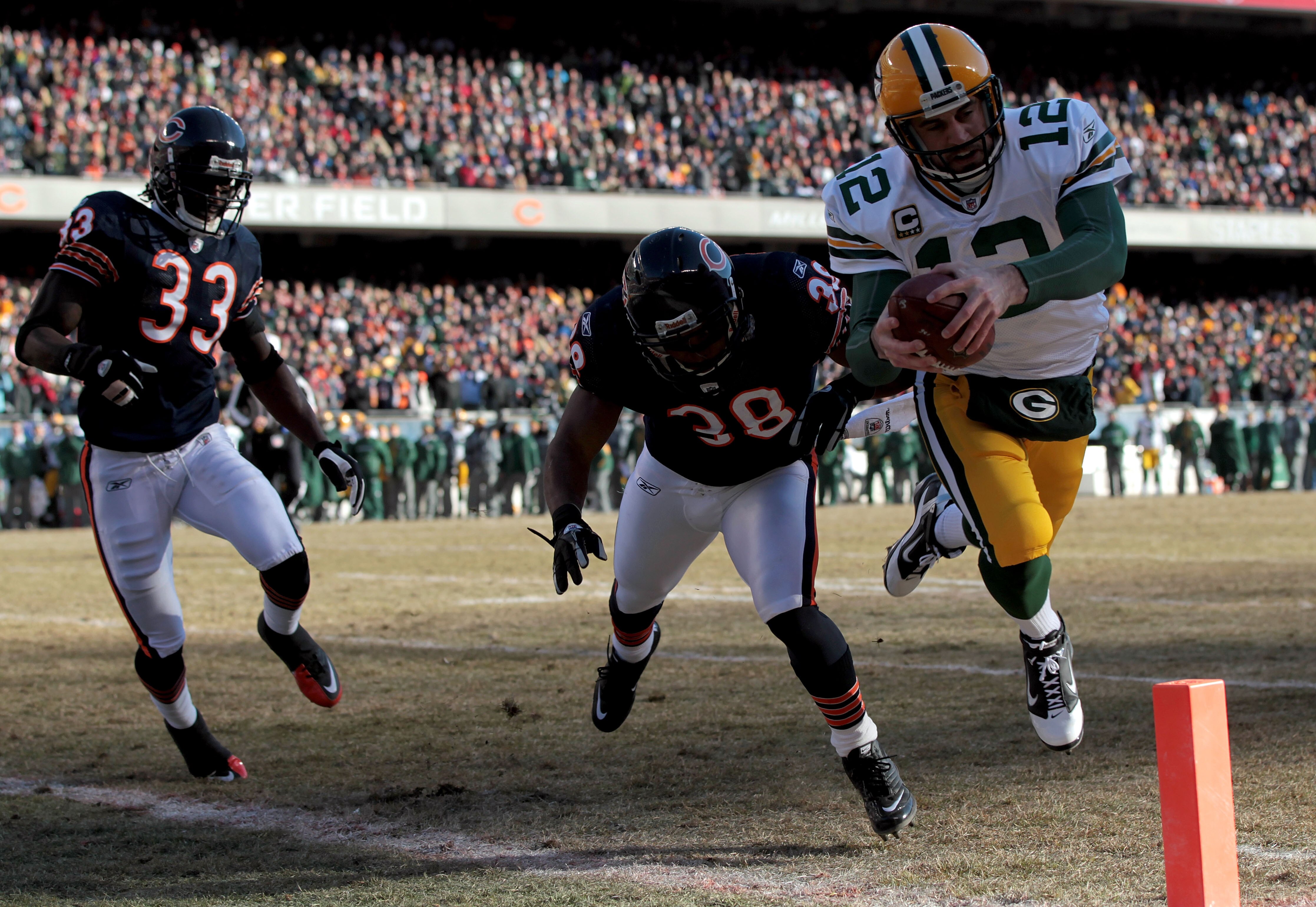 CHICAGO, IL - JANUARY 23:  Quarterback Aaron Rodgers #12 of the Green Bay Packers dives into the corner of the endzone for a one-yard touchdown run against Danieal Manning #38 of the Chicago Bears in the first quarter of the NFC Championship Game at Soldi