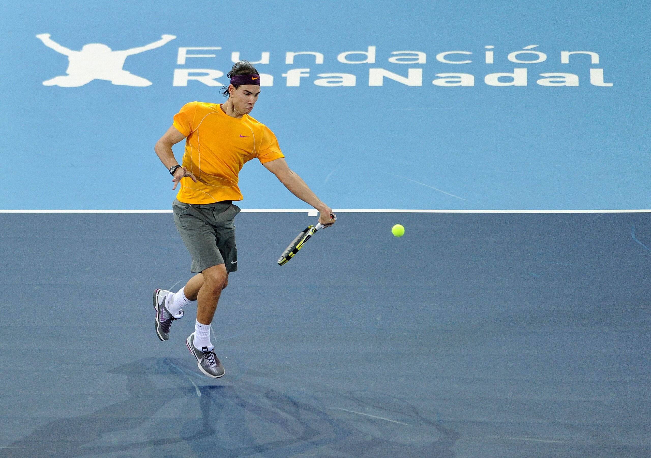 MADRID, SPAIN - DECEMBER 22:  Rafael Nadal of Spain jumps to play a backhand to Roger Federer of Switzerland in a charity exhibition match at La Caja Magica on December 22, 2010 in Madrid, Spain.  (Photo by Jasper Juinen/Getty Images)