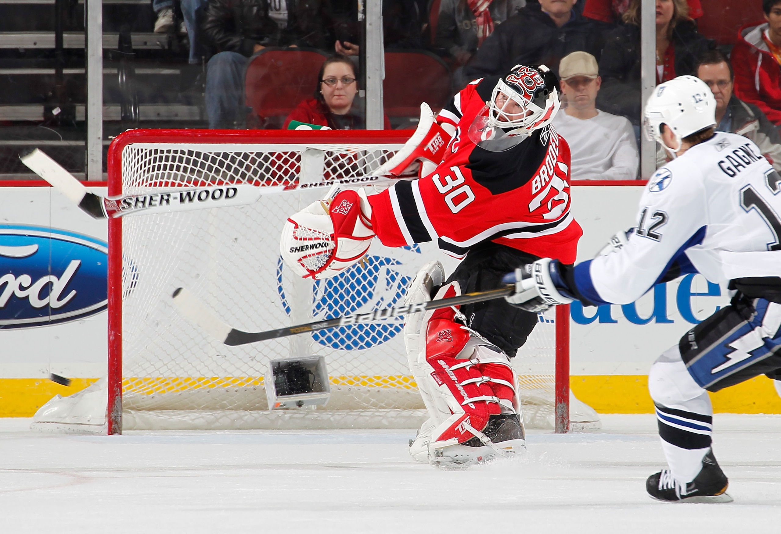 NEWARK, NJ - JANUARY 09:  Martin Brodeur #30 of the New Jersey Devils clears the puck from in front of Simon Gagne #12 of the Tampa Bay Lightning in the second period of an NHL hockey game at the Prudential Center on January 9, 2011 in Newark, New Jersey.