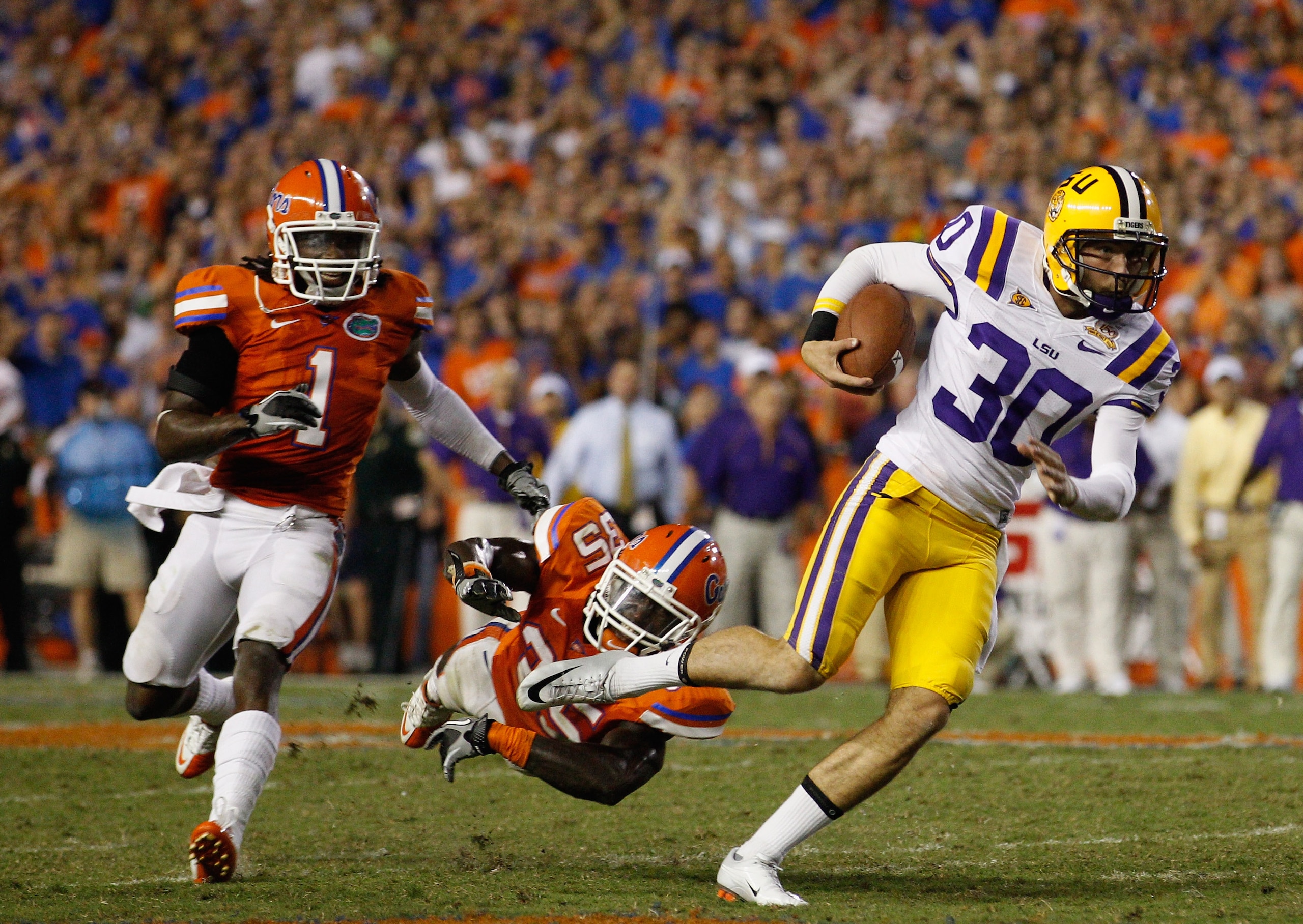 GAINESVILLE, FL - OCTOBER 09:  Punter Josh Jasper #30 of the Louisiana State Tigers runs a fake punt for yardage past Ahmad Black #35 and Janoris Jenkins #1 of the Florida Gators during the game at Ben Hill Griffin Stadium on October 9, 2010 in Gainesvill