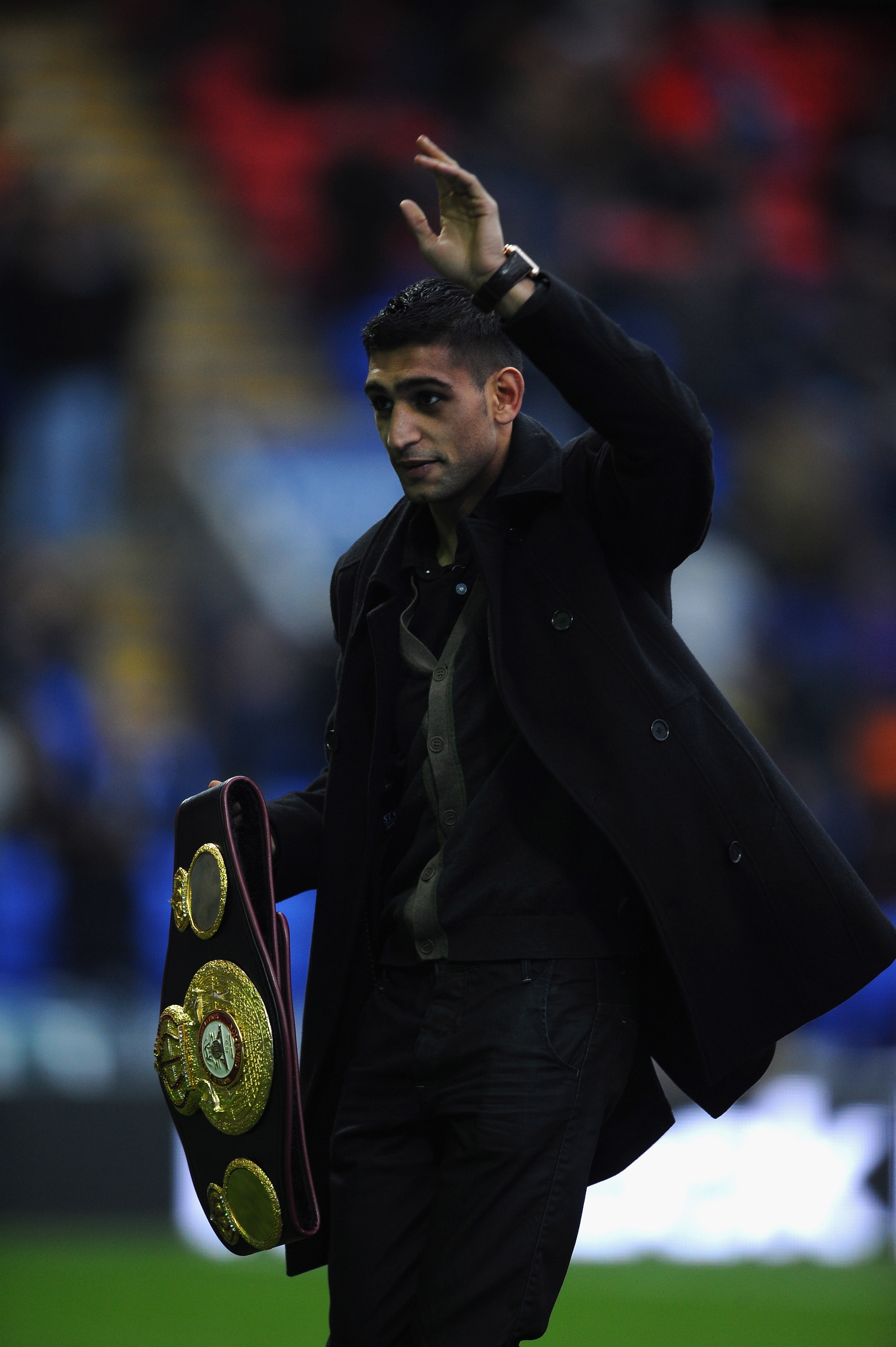 BOLTON, ENGLAND - DECEMBER 26:  Boxer Amir Khan shows his latest belt to the crowd during the Barclays Premier League match between Bolton Wanderers and West Bromwich Albion at Reebok Stadium on December 26, 2010 in Bolton, England.  (Photo by Laurence Gr
