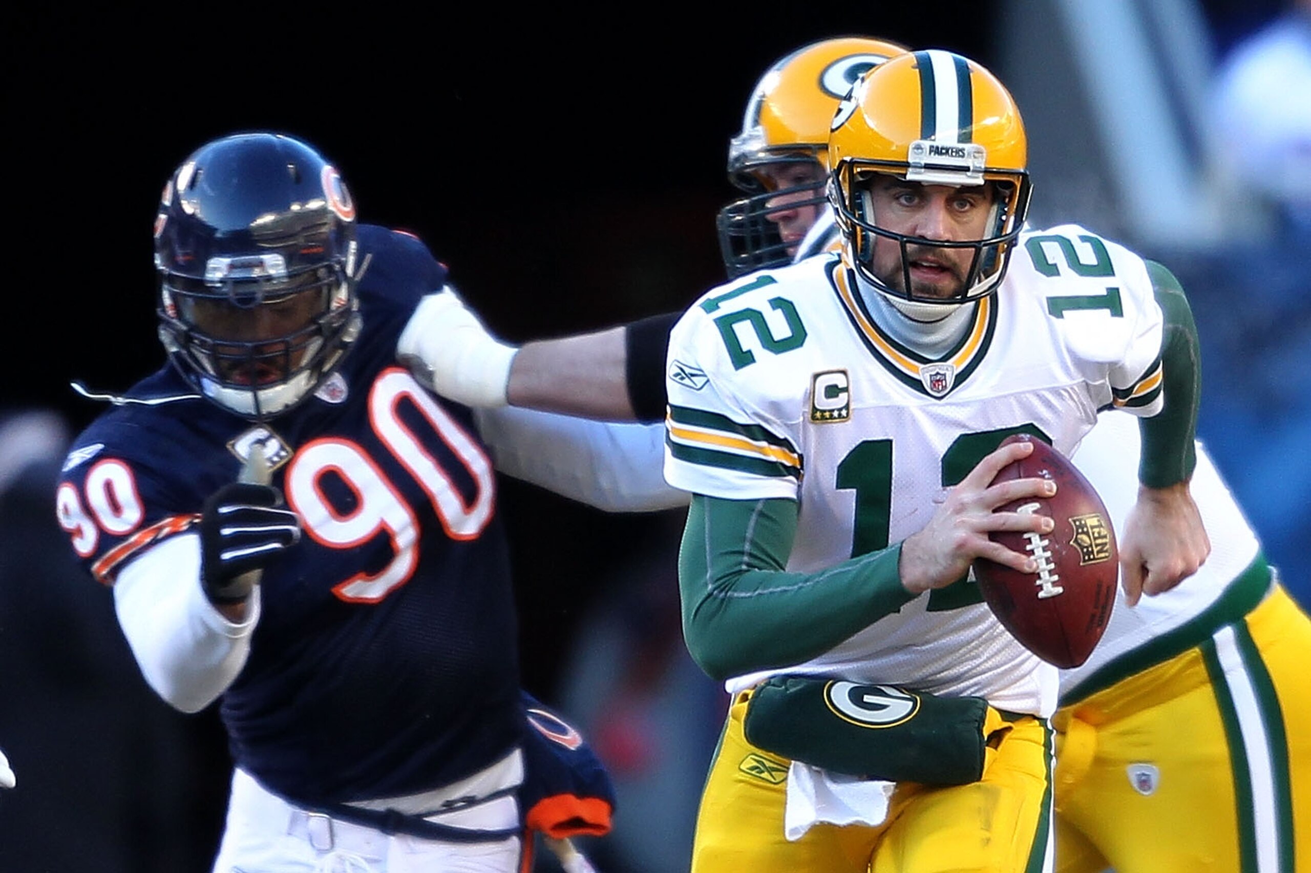 CHICAGO, IL - JANUARY 23:  Quarterback Aaron Rodgers #12 of the Green Bay Packers runs the ball ahead of Julius Peppers #90 of the Chicago Bears in the NFC Championship Game at Soldier Field on January 23, 2011 in Chicago, Illinois.  (Photo by Andy Lyons/