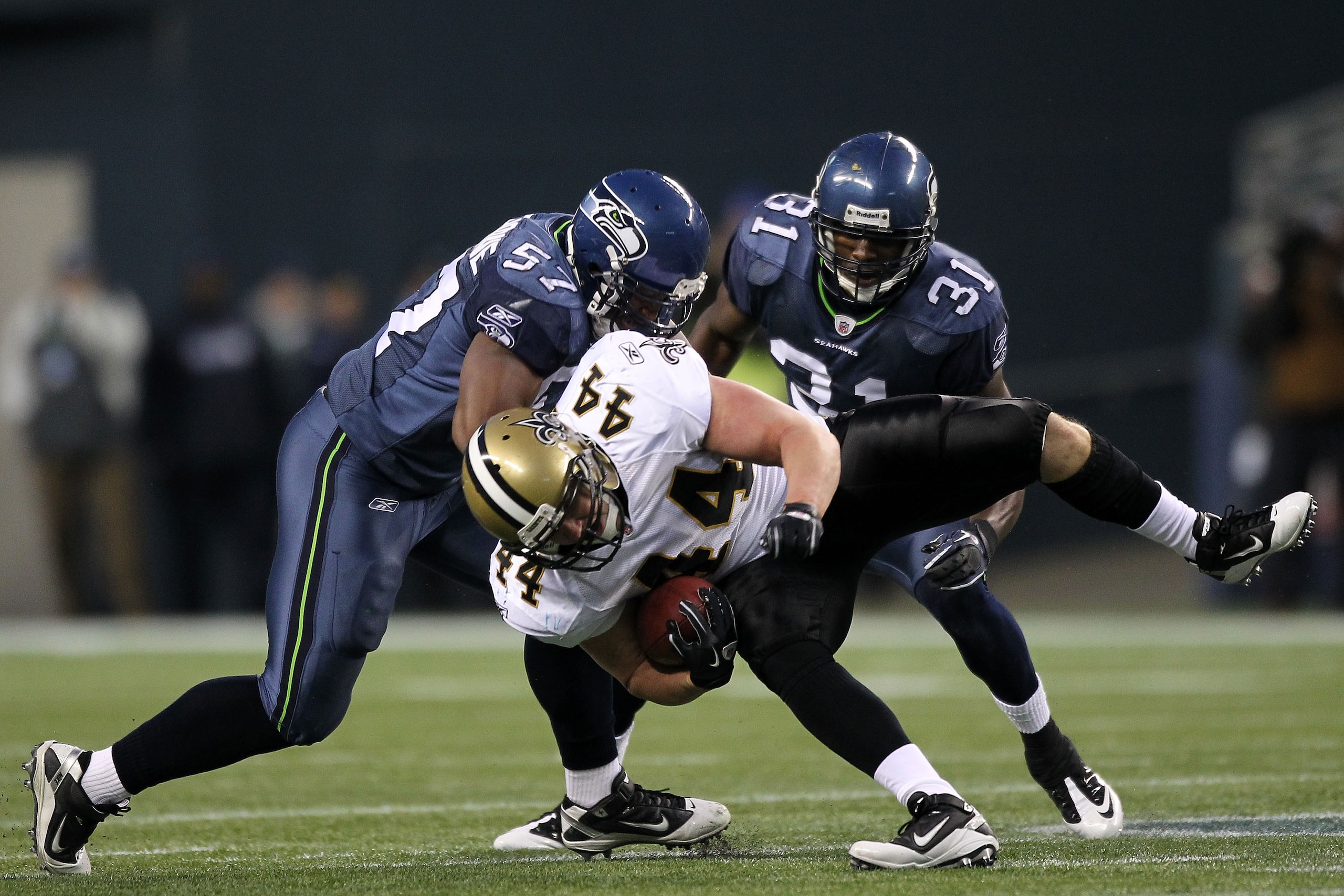 SEATTLE, WA - JANUARY 08:  Heath Evans #44 of the New Orleans Saints is tackled by David Hawthorne #57 and Kam Chancellor #31 of the Seattle Seahawks during the 2011 NFC wild-card playoff game at Qwest Field on January 8, 2011 in Seattle, Washington.  (Ph