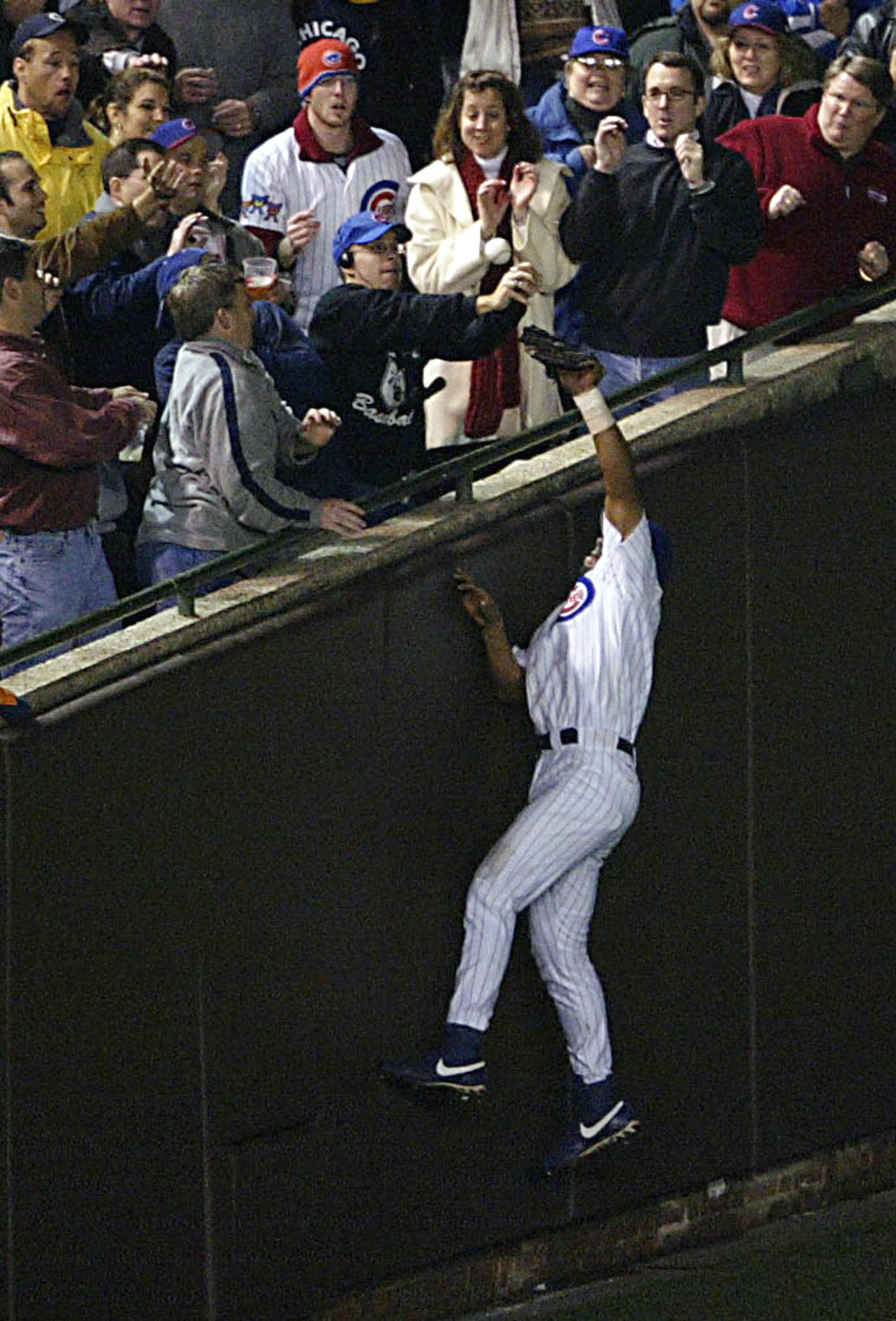 CHICAGO - OCTOBER 14:  Fans interfere with outfielder Moises Alou #18 of the Chicago Cubs on a ball hit by Luis Castillo #1 of the Florida Marlins in the eighth inning during Game 6 of the National League Championship Series October 14, 2003 at Wrigley Fi