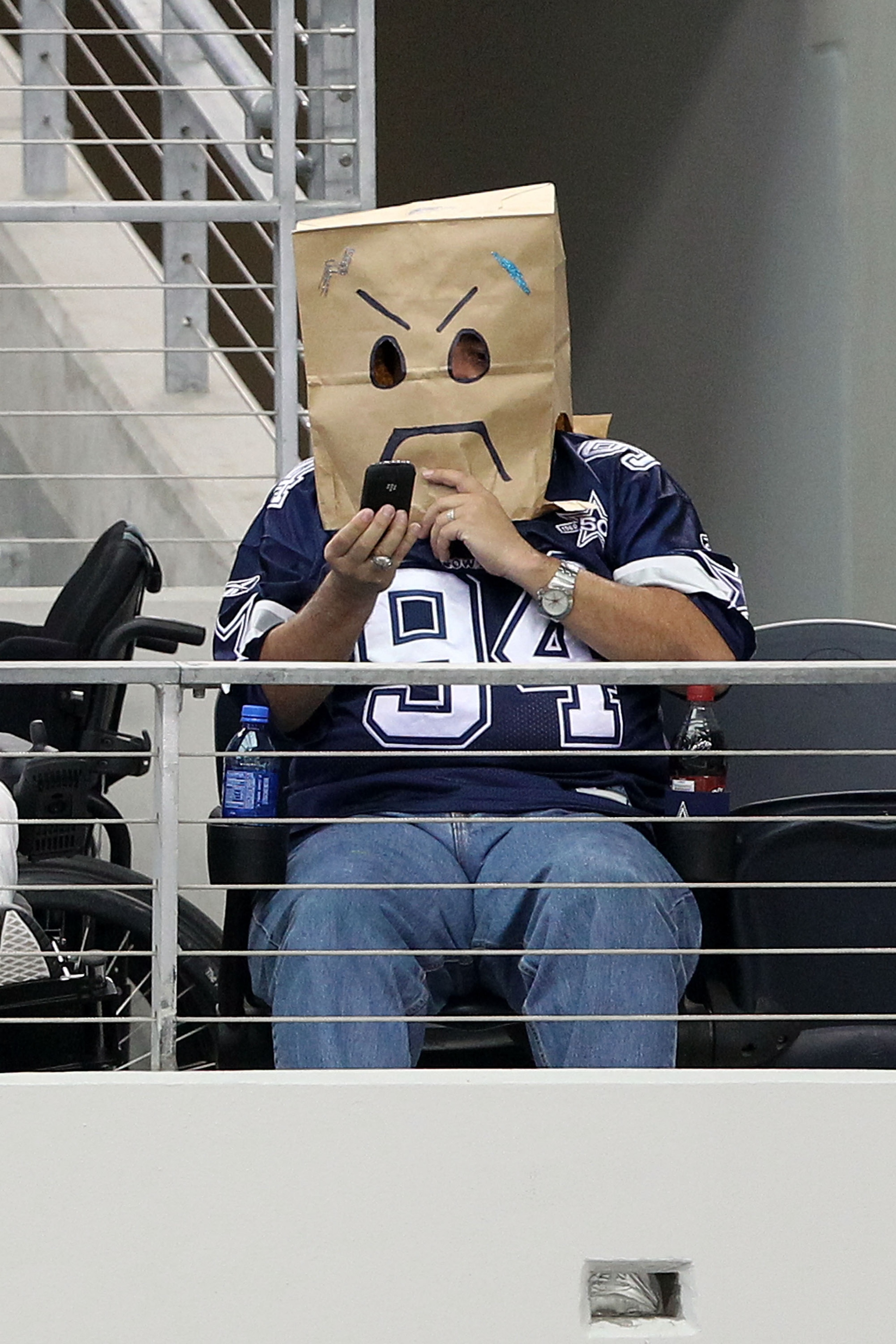 ARLINGTON, TX - OCTOBER 31:  A fan of the Dallas Cowboys wears a brown paper bag on his  head as he looks at his phone against the Jacksonville Jaguars at Cowboys Stadium on October 31, 2010 in Arlington, Texas.  (Photo by Chris Chambers/Getty Images)