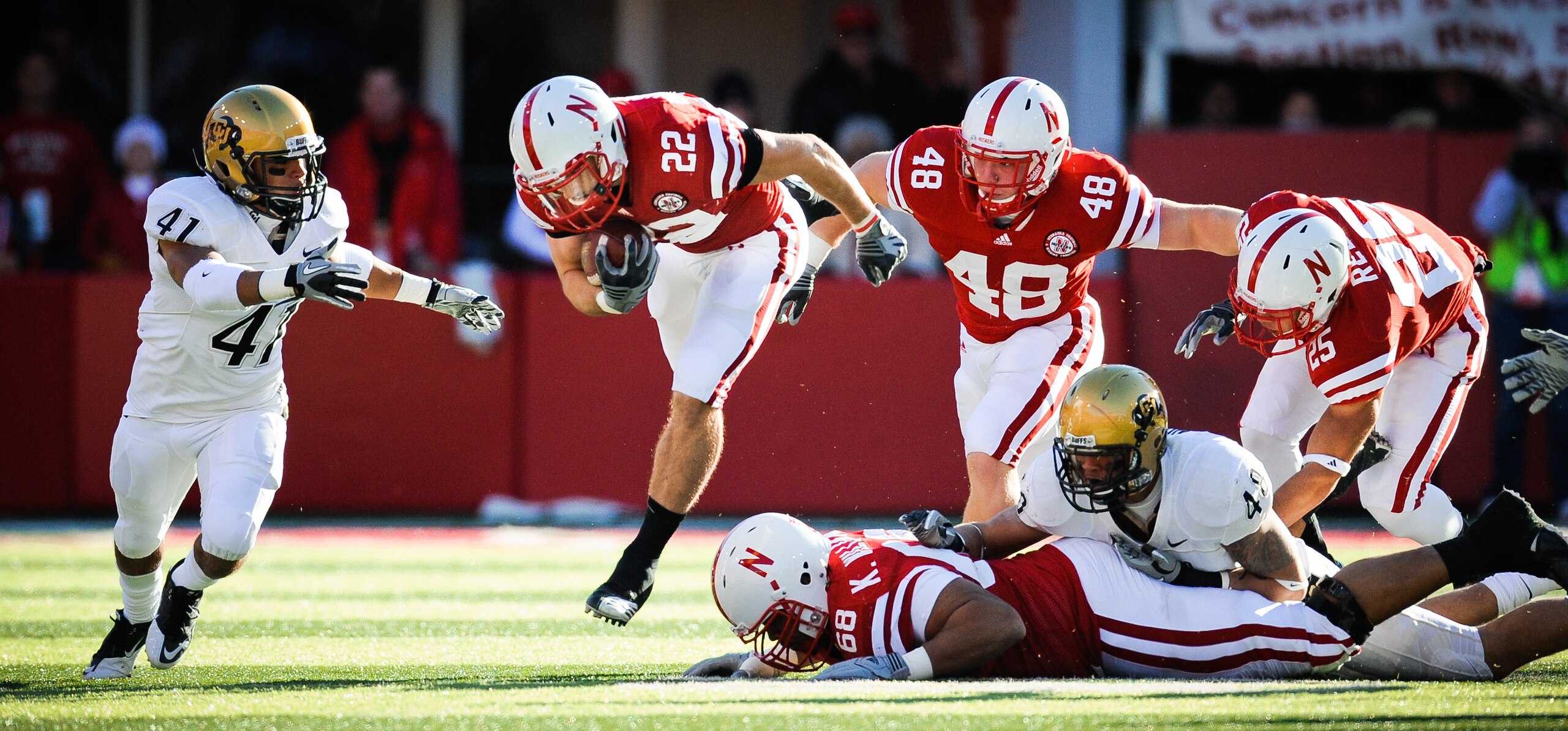 LINCOLN, NE - NOVEMBER 26: Rex Burkhead #22 of the Nebraska Cornhuskers leaps over teammate Keith Williams #68 and is helped by Tyler Legate #48 and Kyler Reed #25 of the Nebraska Cornhuskers during their game against the Colorado Buffaloes at Memorial St