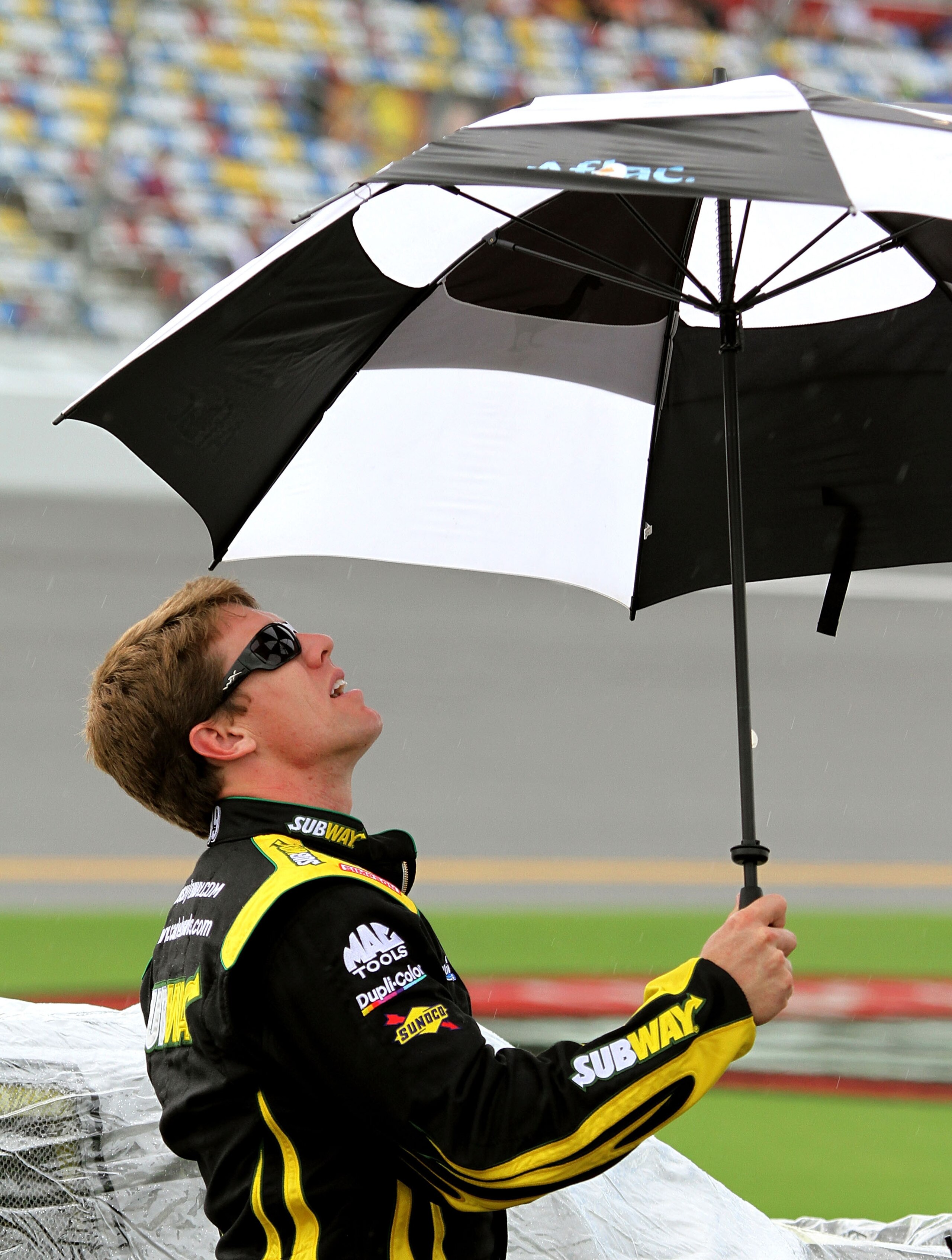 DAYTONA BEACH, FL - JULY 02: Carl Edwards, driver of the #99 SUBWAY Ford, holds an umbrella on the grid as as rain cancels qualifying for the NASCAR Sprint Cup Series Coke Zero 400 at Daytona International Speedway on July 2, 2010 in Daytona Beach, Florid