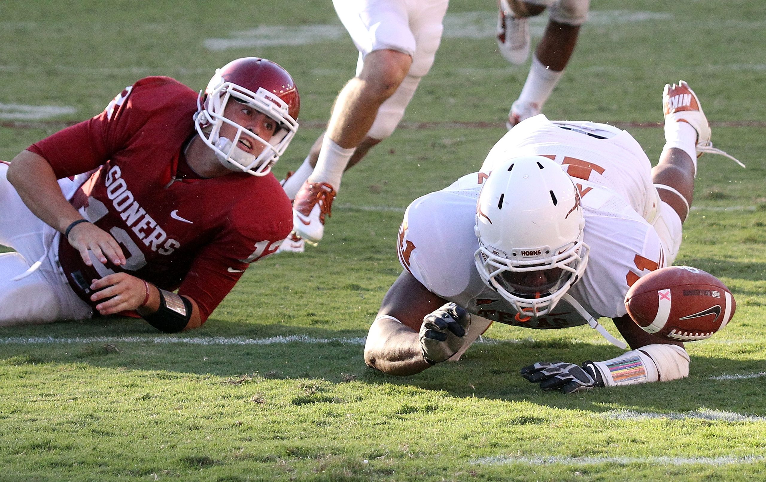 DALLAS - OCTOBER 02:  Quarterback Landry Jones #12 of the Oklahoma Sooners fumbles the ball out of play in front of Jared Norton #11 of the Texas Longhorns in the fourth quarter at the Cotton Bowl on October 2, 2010 in Dallas, Texas.  (Photo by Ronald Mar