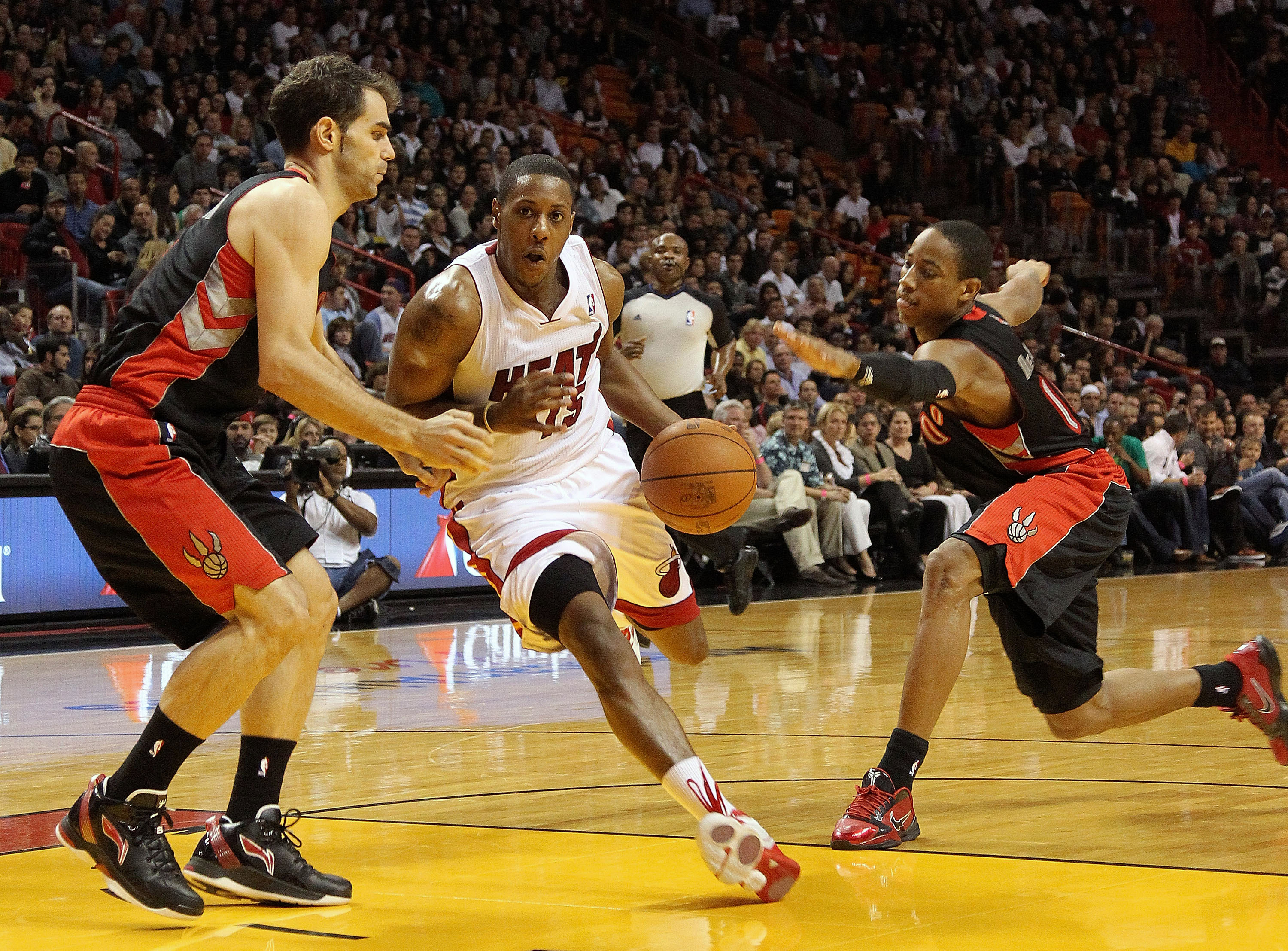 MIAMI, FL - JANUARY 22: Mario Chalmers #15 of the Miami Heat dribbles through DeMar DeRozan #10 and Jose Calderon #8 of the Toronto Raptors during a game at American Airlines Arena on January 22, 2011 in Miami, Florida. NOTE TO USER: User expressly acknow