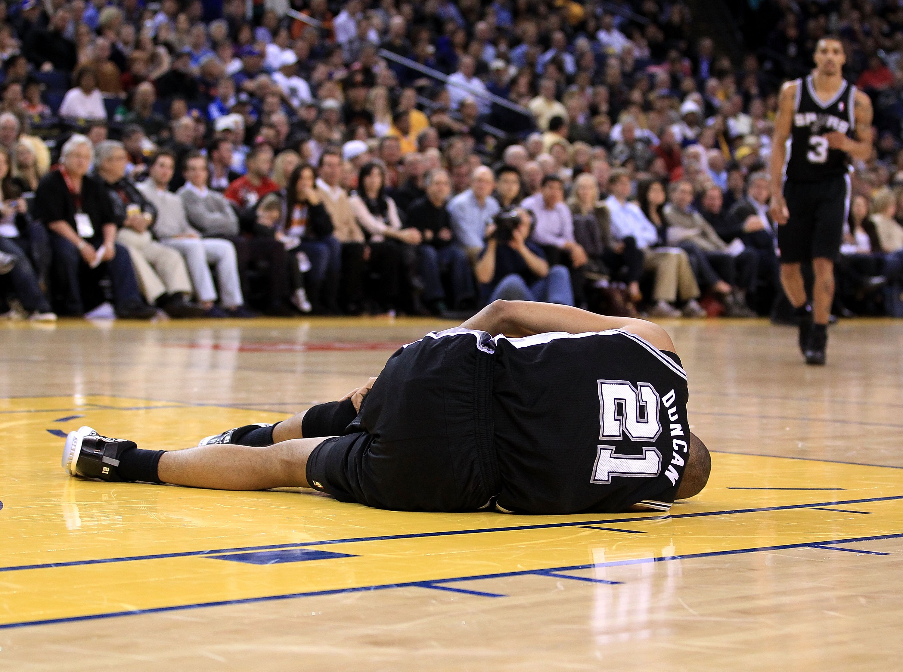 OAKLAND, CA - JANUARY 24:  Tim Duncan #21 of the San Antonio Spurs lies on the court after injuring his knee during their game against the Golden State Warriors at Oracle Arena on January 24, 2011 in Oakland, California.  NOTE TO USER: User expressly ackn