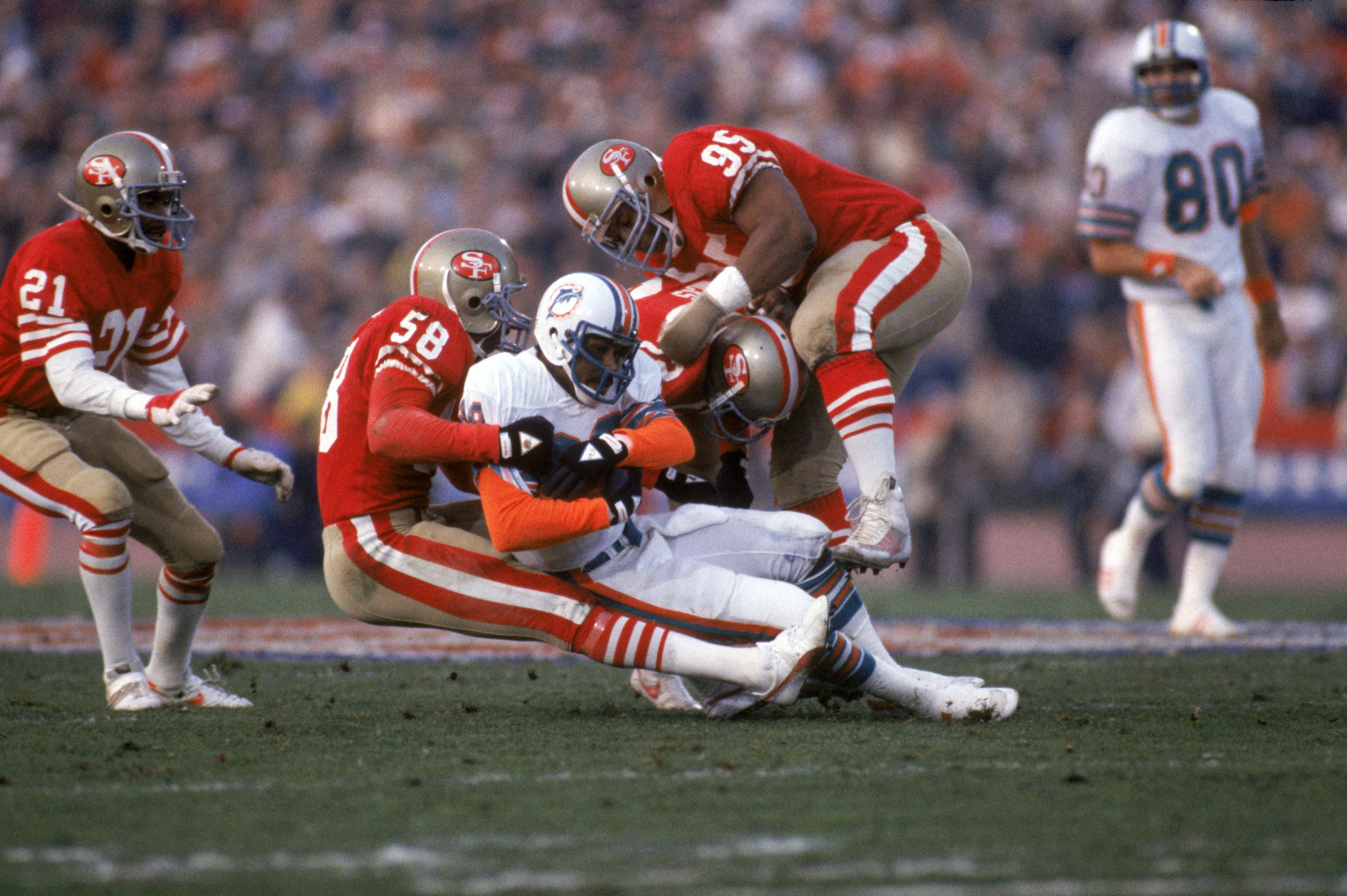 STANFORD, CA - JANUARY 20:  Linebacker Keena Turner #58 and defensive tackle Michael Carter #95 of the San Francisco 49ers tackle Miami Dolphins wide receiver Nat Moore #89 during Super Bowl XIX at Stanford Stadium on January 20, 1985 in Stanford, Califor