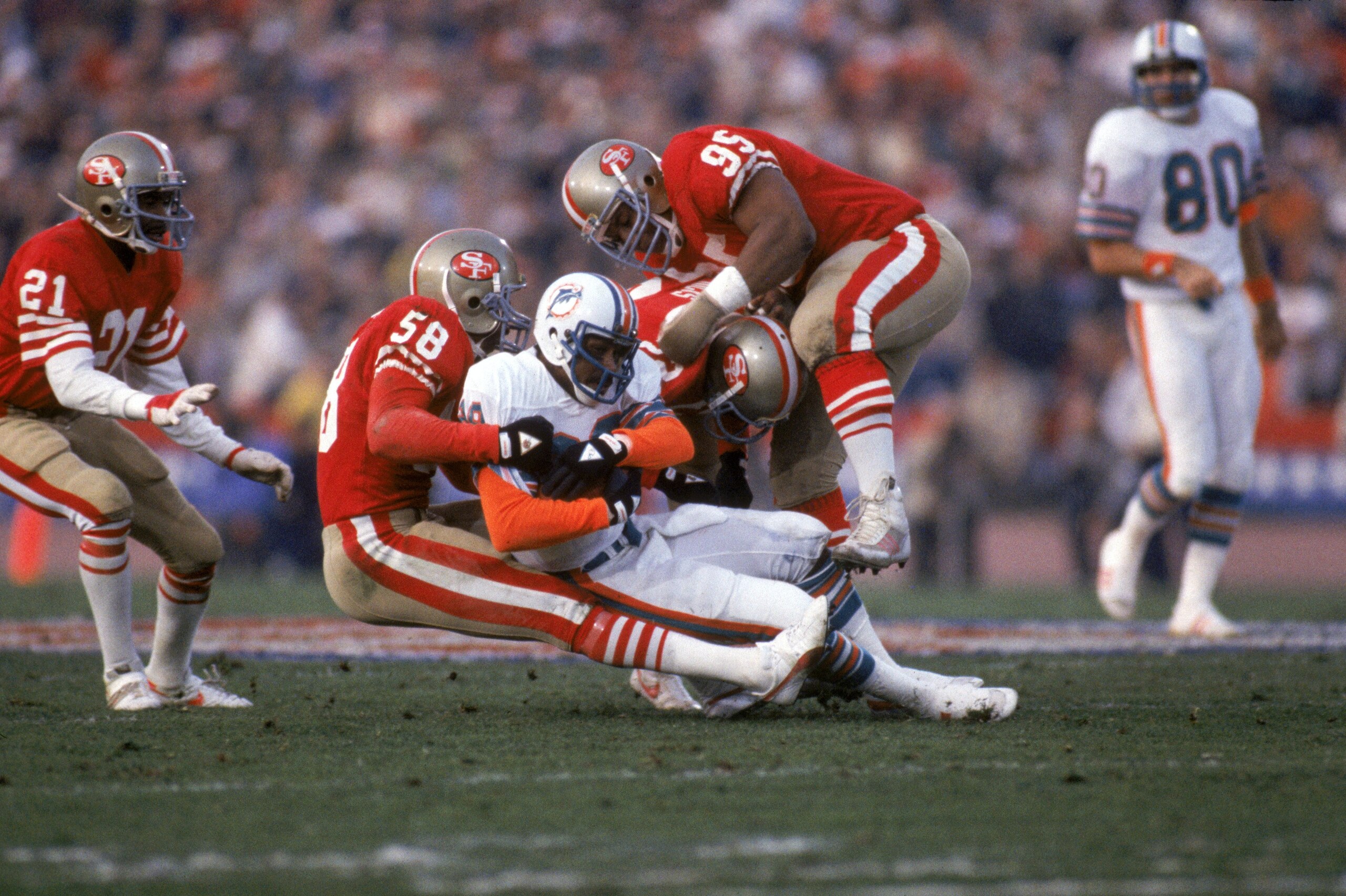 STANFORD, CA - JANUARY 20:  Linebacker Keena Turner #58 and defensive tackle Michael Carter #95 of the San Francisco 49ers tackle Miami Dolphins wide receiver Nat Moore #89 during Super Bowl XIX at Stanford Stadium on January 20, 1985 in Stanford, Califor