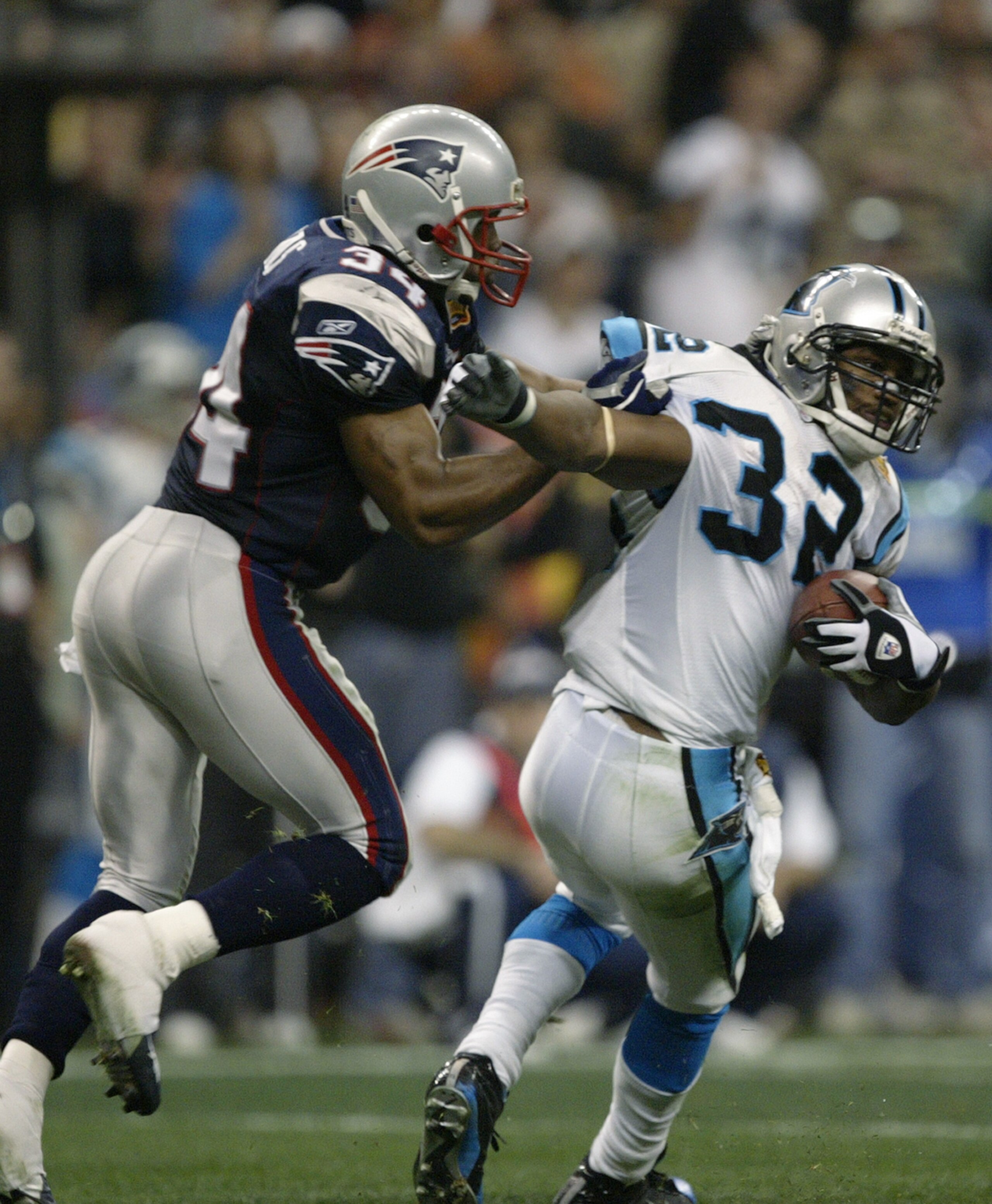HOUSTON - FEBRUARY 1:  Safety Chris Akins #34 of the New England Patriots attempts to tackle Rod Smart #32 of the Carolina Panthers during Super Bowl XXXVIII at Reliant Stadium on February 1, 2004 in Houston, Texas.  The Patriots defeated the Panthers 32-