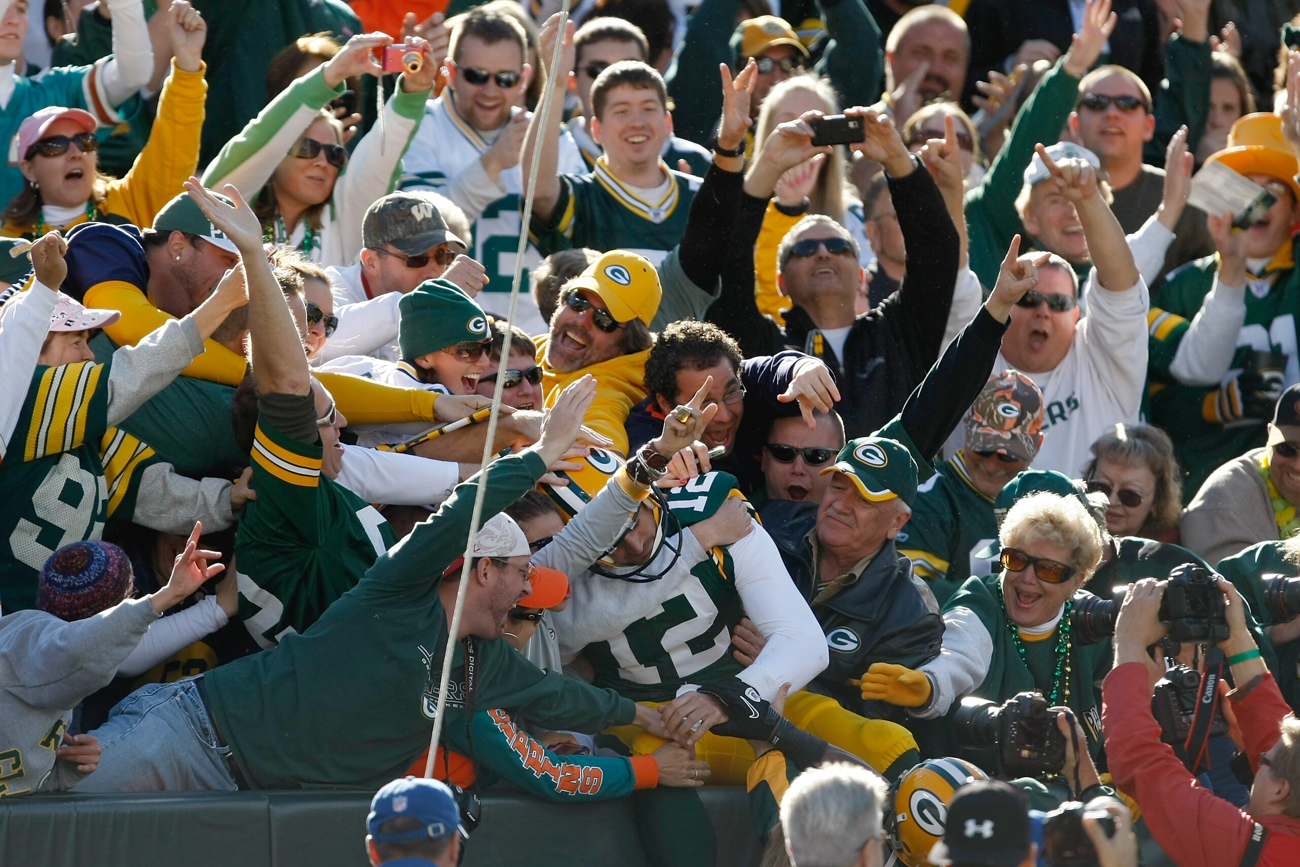 GREEN BAY, WI - OCTOBER 17: Aaron Rogers #12 of the Green Bay Packers jumps in the stands to celebrate a touchdown to tie the game against the Miami Dolphins at Lambeau Field on October 17, 2010 in Green Bay, Wisconsin. The Dolphins defeated the Packers 2