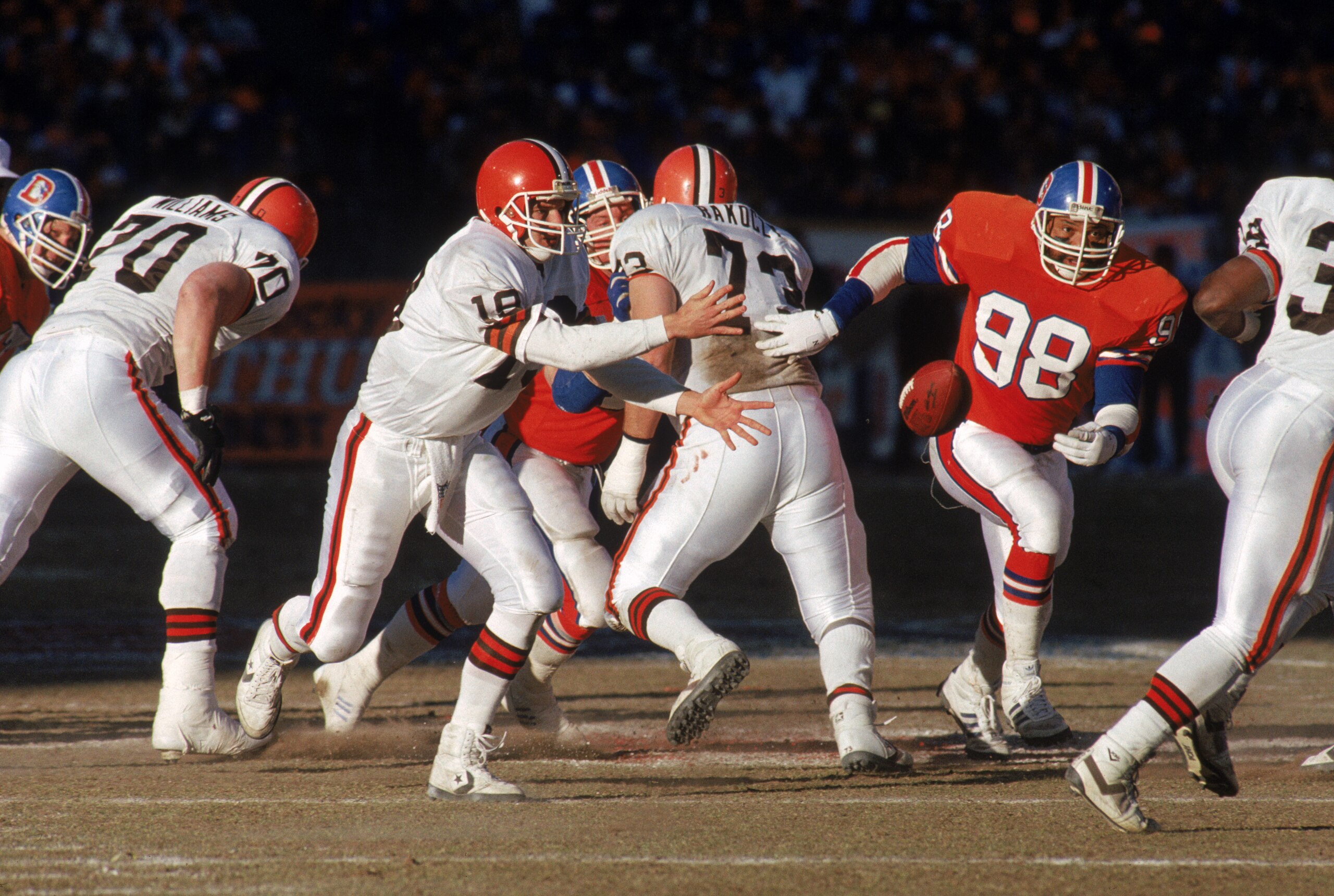 DENVER - JANUARY 17:  Quarterback Bernie Kosar #19 of the Cleveland Browns pitches the ball to his right as linebacker Ricky Hunley #98 of the Denver Broncos approaches during the 1987 AFC Championship game at Mile High Stadium on January 17, 1988 in Denv