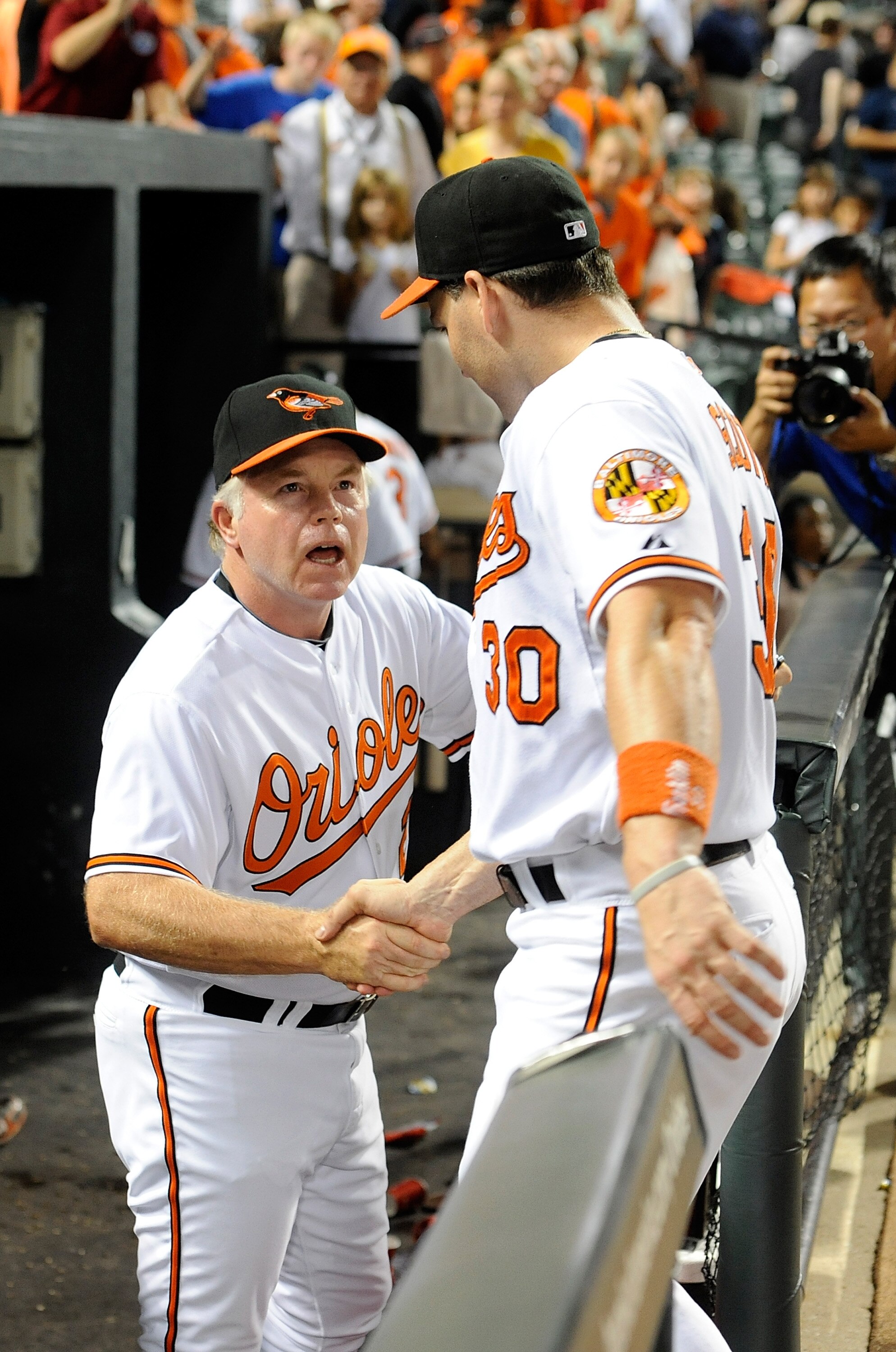 BALTIMORE - AUGUST 03:  Manager Buck Showalter of the Baltimore Orioles celebrates with Luke Scott #30 after a 6-3 victory against the Los Angeles Angels of Anaheim at Camden Yards on August 3, 2010 in Baltimore, Maryland.  (Photo by Greg Fiume/Getty Imag