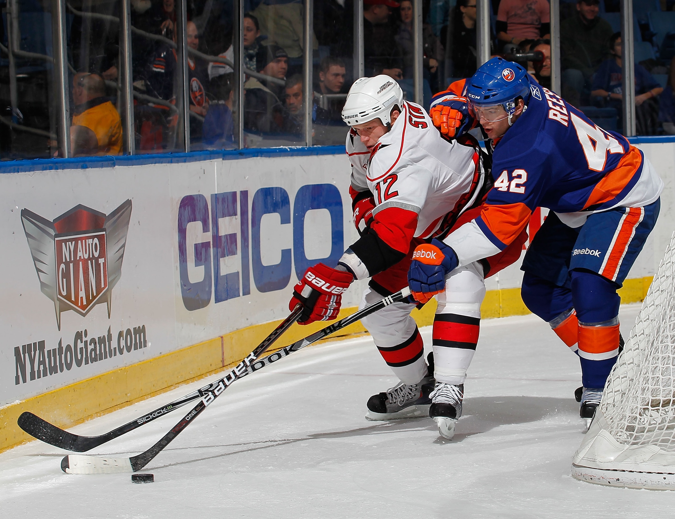 UNIONDALE, NY - JANUARY 26:  Eric Staal #12 of the Carolina Hurricanes is checked by Dylan Reese #42 of the New York Islanders during the first period of an NHL hockey game at the Nassau Coliseum on January 26, 2011 in Uniondale, New York.  (Photo by Paul