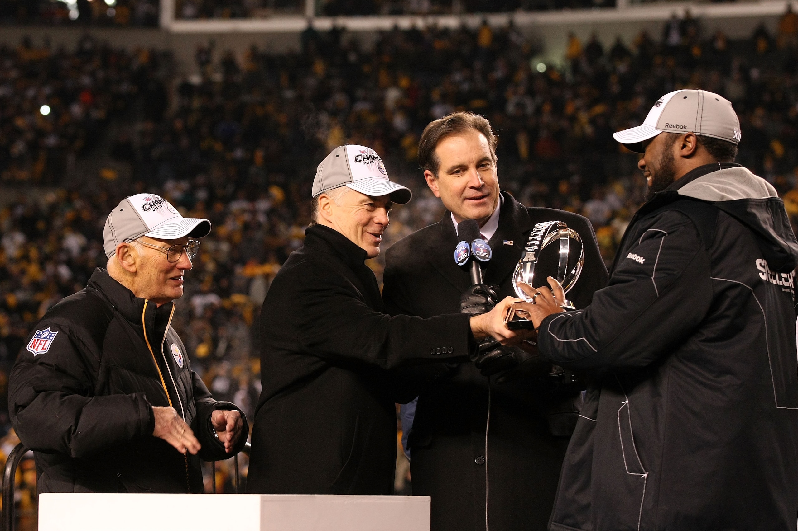 PITTSBURGH, PA - JANUARY 23:  Owner Dan Rooney (L), Team president Art Rooney II (2ndL),  and head coach Mike Tomlin (R) of the Pittsburgh Steelers recieve the Lamar Hunt Trophy as CBS sportscaster Jim Nantz looks on after their 24 to 19 win over the New