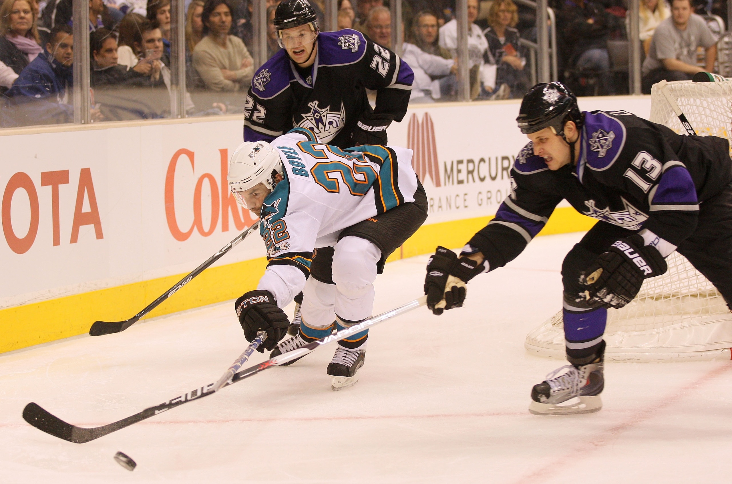 LOS ANGELES, CA - JANUARY 26:  Dan Boyle #22 of the San Jose Sharks reaches for the puck as Kyle Clifford #13 of the Los Angeles Kings defends at Staples Center on January 26, 2011 in Los Angeles, California.  (Photo by Victor Decolongon/Getty Images)