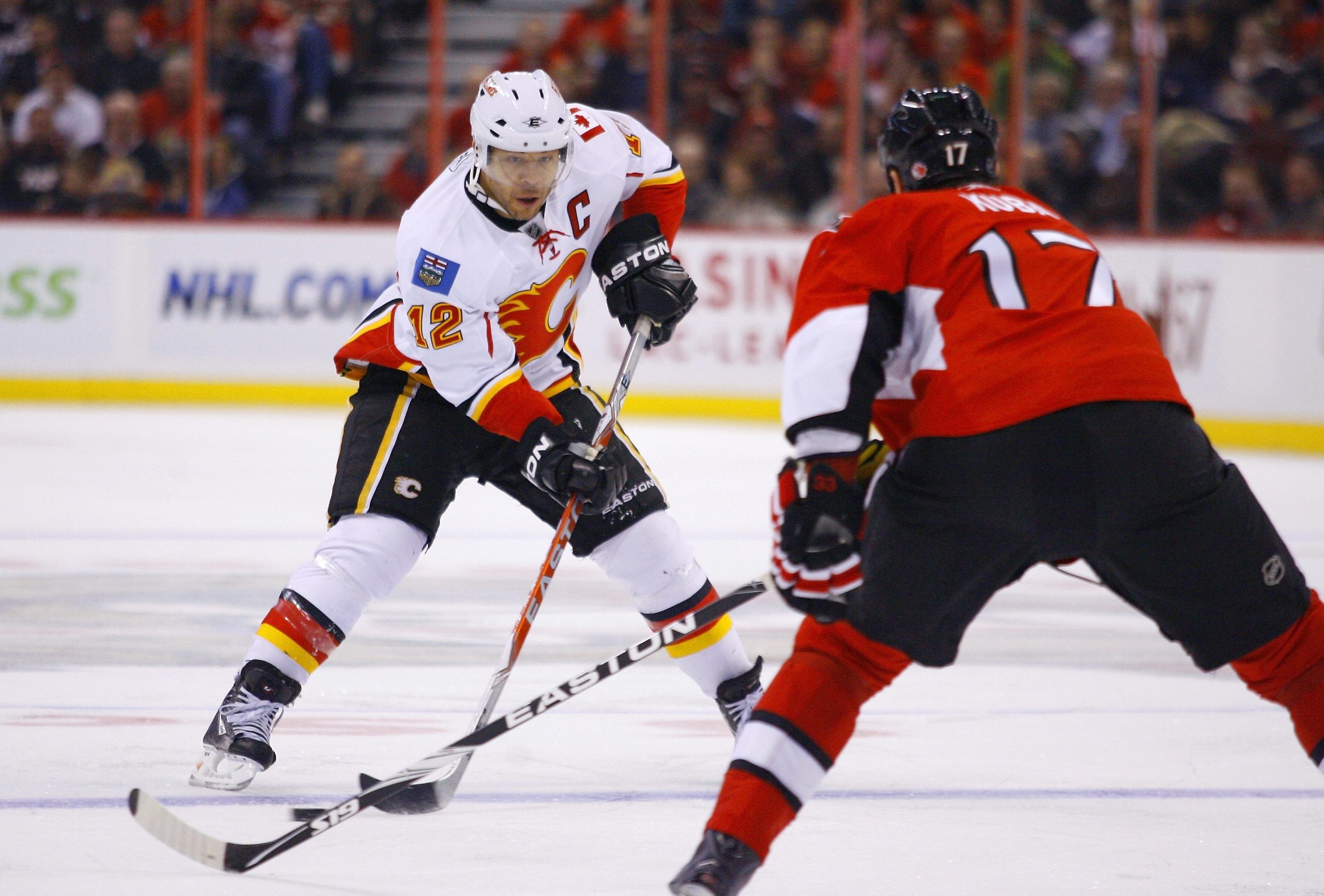 OTTAWA, ON - JANUARY 14:  Jarome Iginla #12 of the Calgary Flames carries the puck up ice while being watched by Filip Kuba #17 of the Ottawa Senators in a game at Scotiabank Place on January 14, 2011 in Ottawa, Canada. The Flames won 3-2. (Photo by Phill