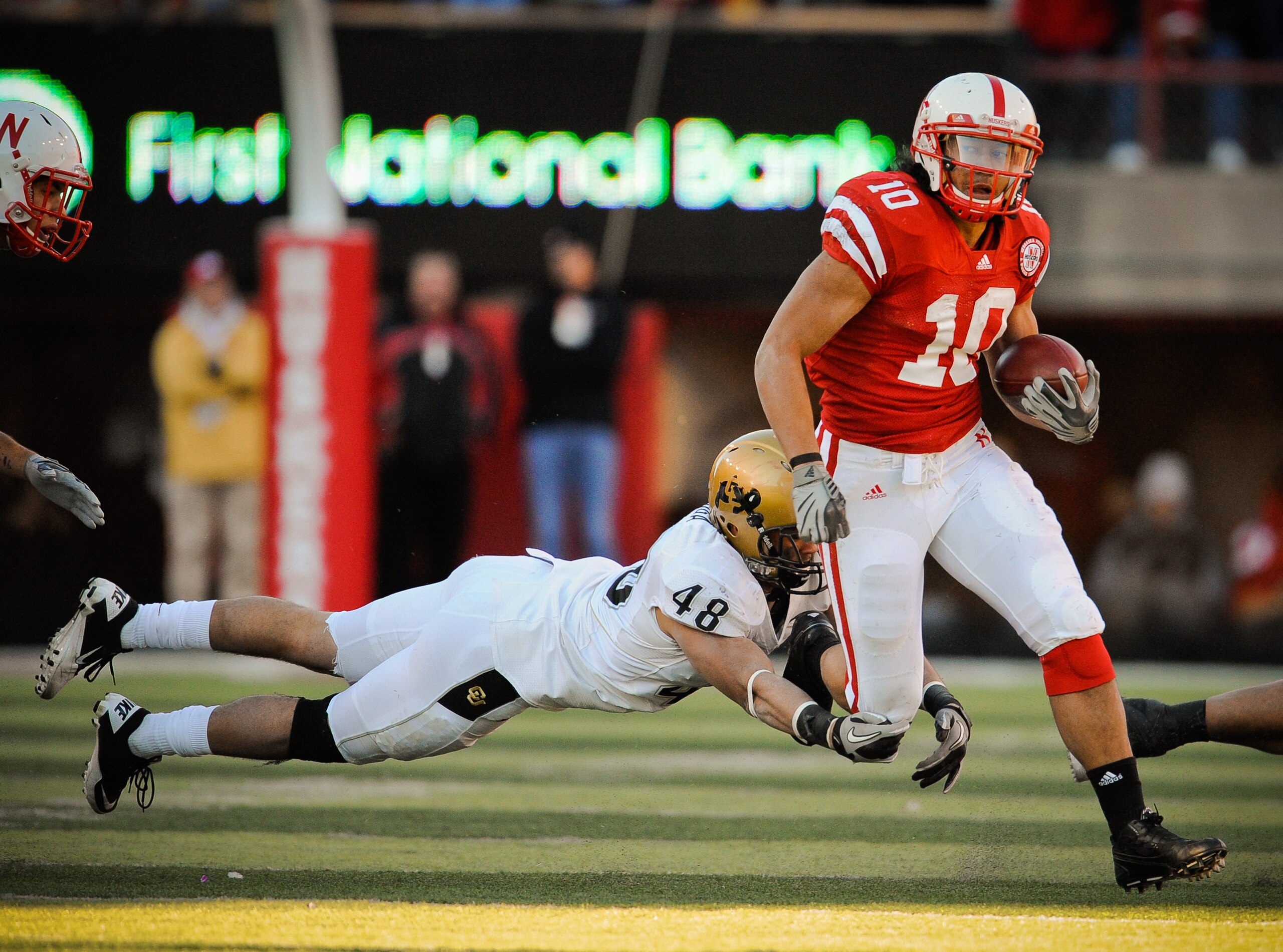 LINCOLN, NE - NOVEMBER 26: Roy Helu Jr. #10 of the Nebraska Cornhuskers runs past Liloa Nobriga #48 of the Colorado Buffaloes during the first half of their game at Memorial Stadium on November 26, 2010 in Lincoln, Nebraska. Nebraska defeated Colorado 45-