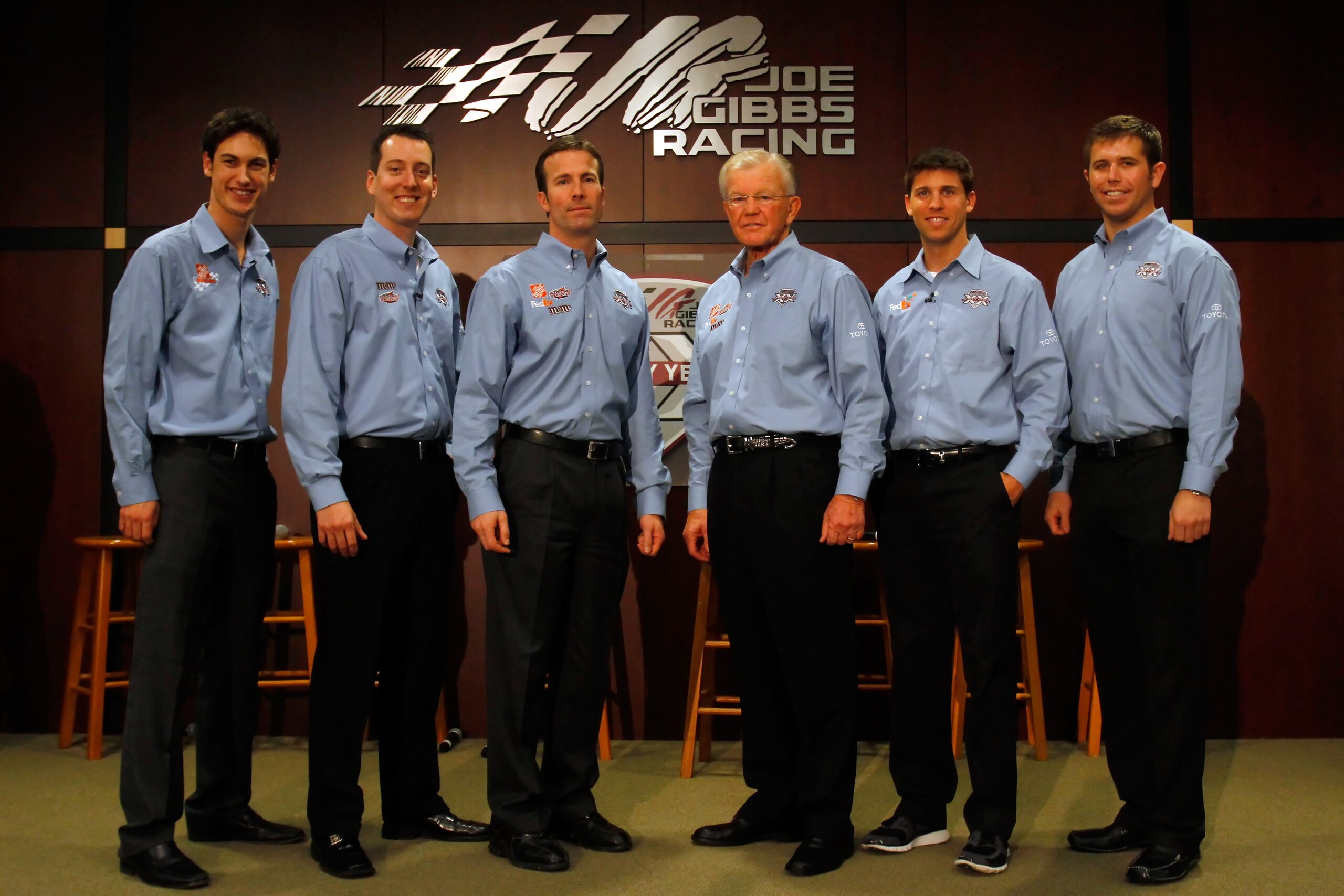 HUNTERSVILLE, NC - JANUARY 27:  Team owner Joe Gibbs (3rd-R) poses with J.D. Gibbs (3rd-L), JGR President, Joey Logano (L), driver of the #20 Home Depot Toyota, Kyle Busch (2nd-L), driver of the #18 M&M's Toyota, Denny Hamlin (2nd-R), driver of the #11 Fe