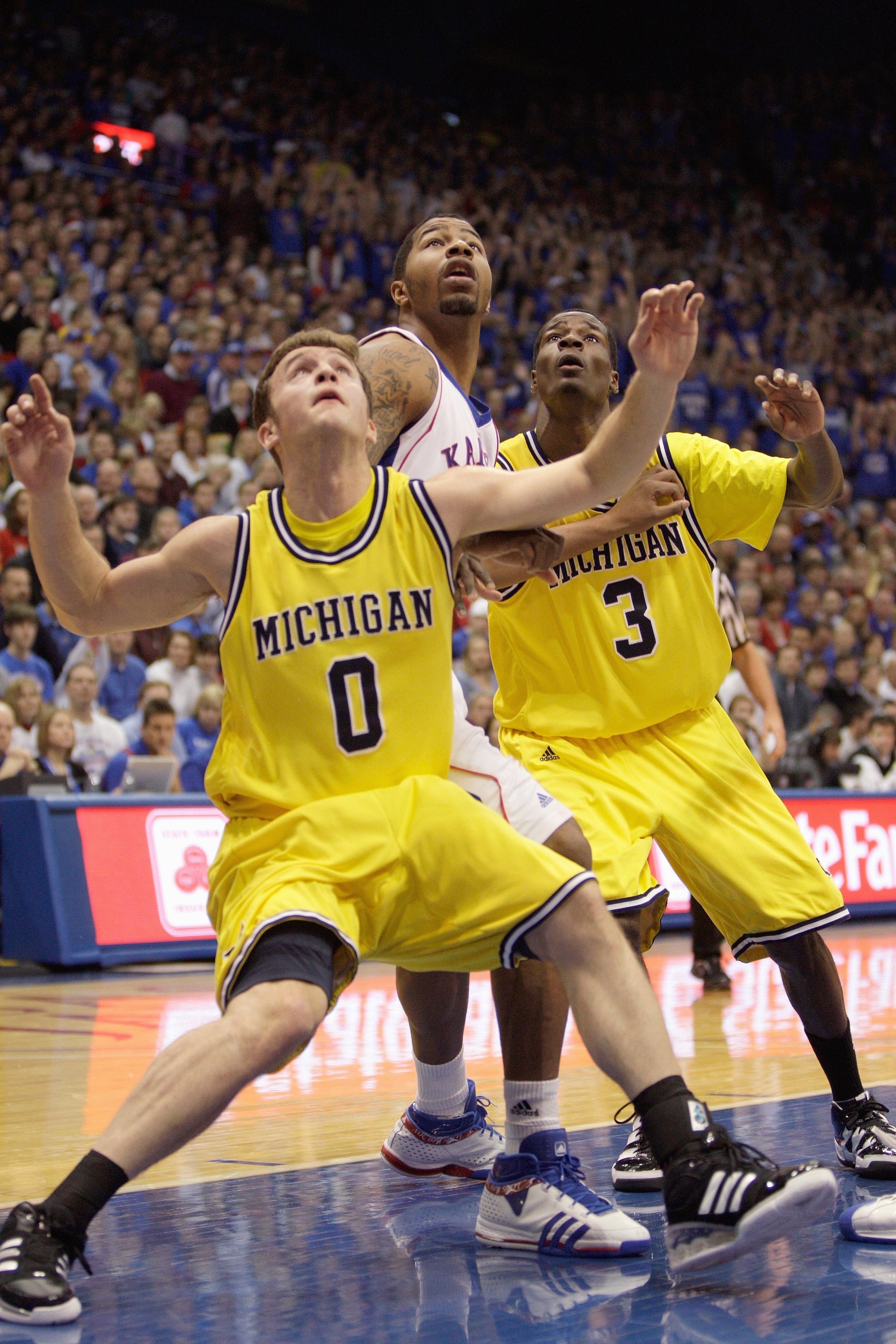 LAWRENCE, KS - DECEMBER 19:  Marcus Morris #22 of the Kansas Jayhawks looks to rebound the ball against Zack Novak #0 and Manny Harris #3 of the Michigan Wolverines on December 19, 2009 at Allen Fieldhouse in Lawrence, Kansas. (Photo by Jamie Squire/Getty