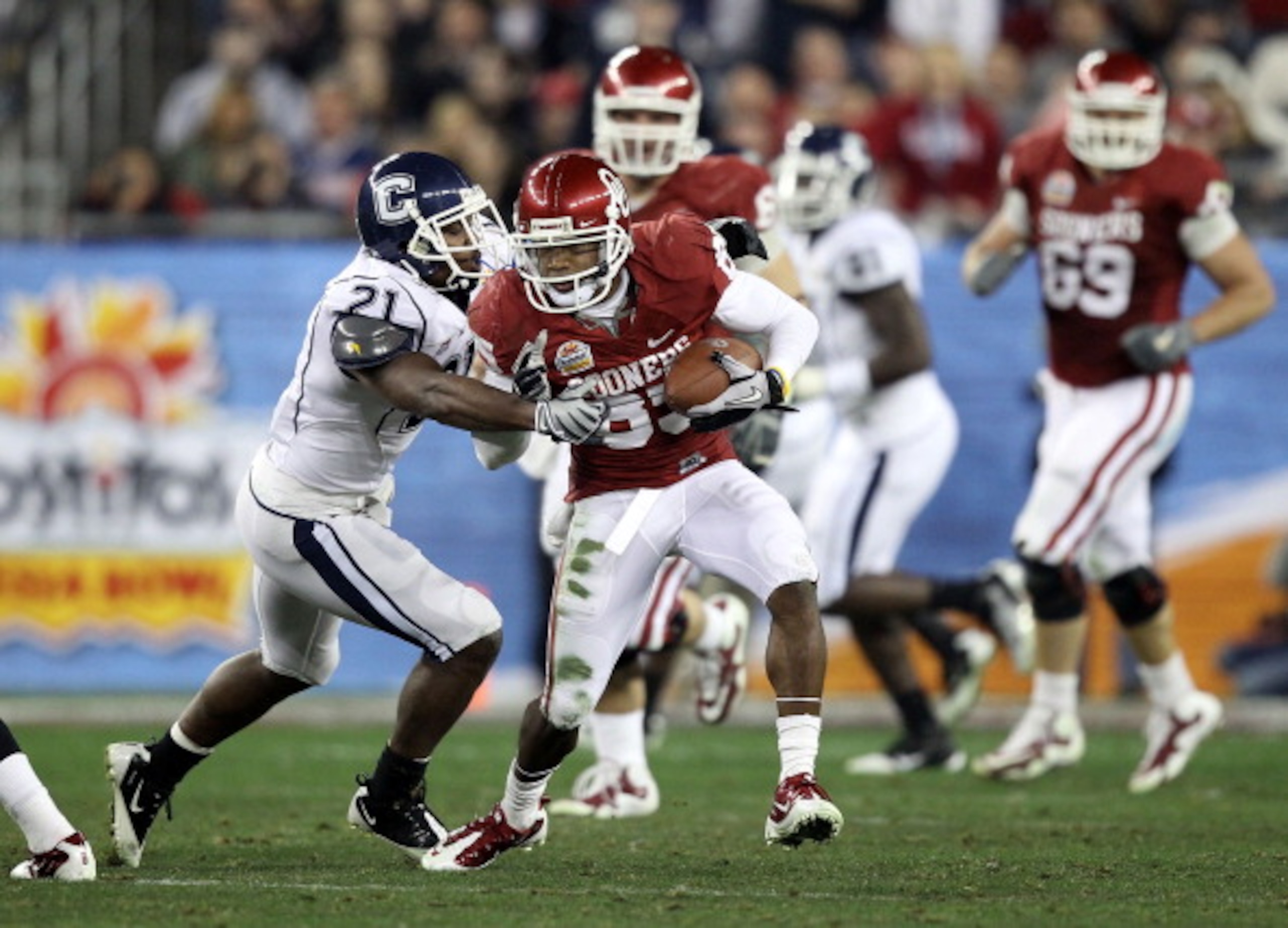 GLENDALE, AZ - JANUARY 01: Ryan Broyles #85 of the Oklahoma Sooners of the Oklahoma Sooners runs after a catch as Gary Wilburn #21 of the Connecticut Huskies goes for the tackle during the Tostitos Fiesta Bowl at the Universtity of Phoenix Stadium on Jan GLENDALE, AZ - JANUARY 01: Ryan Broyles #85 of the Oklahoma Sooners of the Oklahoma Sooners runs after a catch as Gary Wilburn #21 of the Connecticut Huskies goes for the tackle during the Tostitos Fiesta Bowl at the Universtity of Phoenix Stadium on Jan