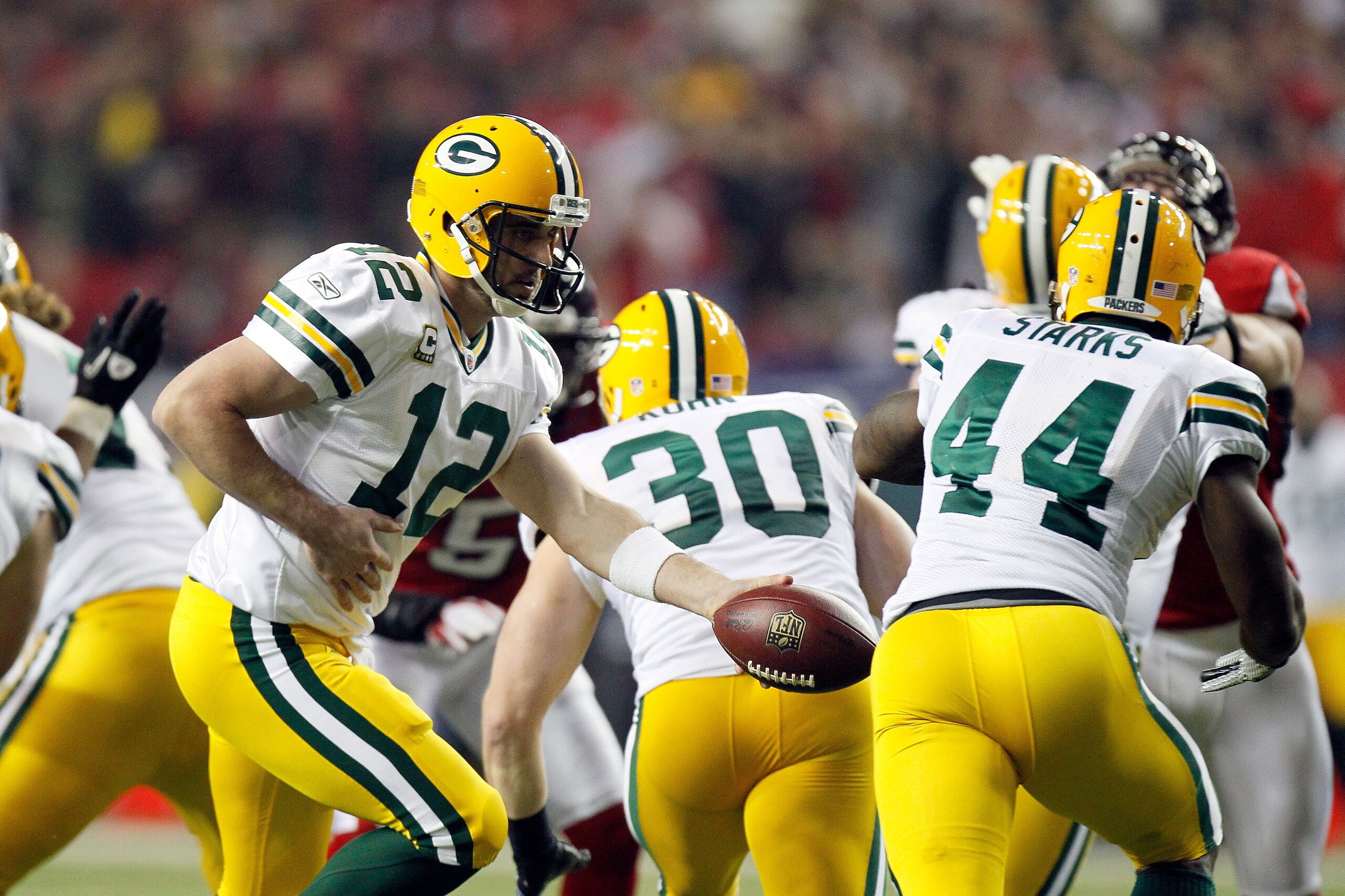 ATLANTA, GA - JANUARY 15:  Quarterback Aaron Rodgers #12 of the Green Bay Packers turns to hand the ball off to James Starks #44 against the Atlanta Falcons during their 2011 NFC divisional playoff game at Georgia Dome on January 15, 2011 in Atlanta, Geor