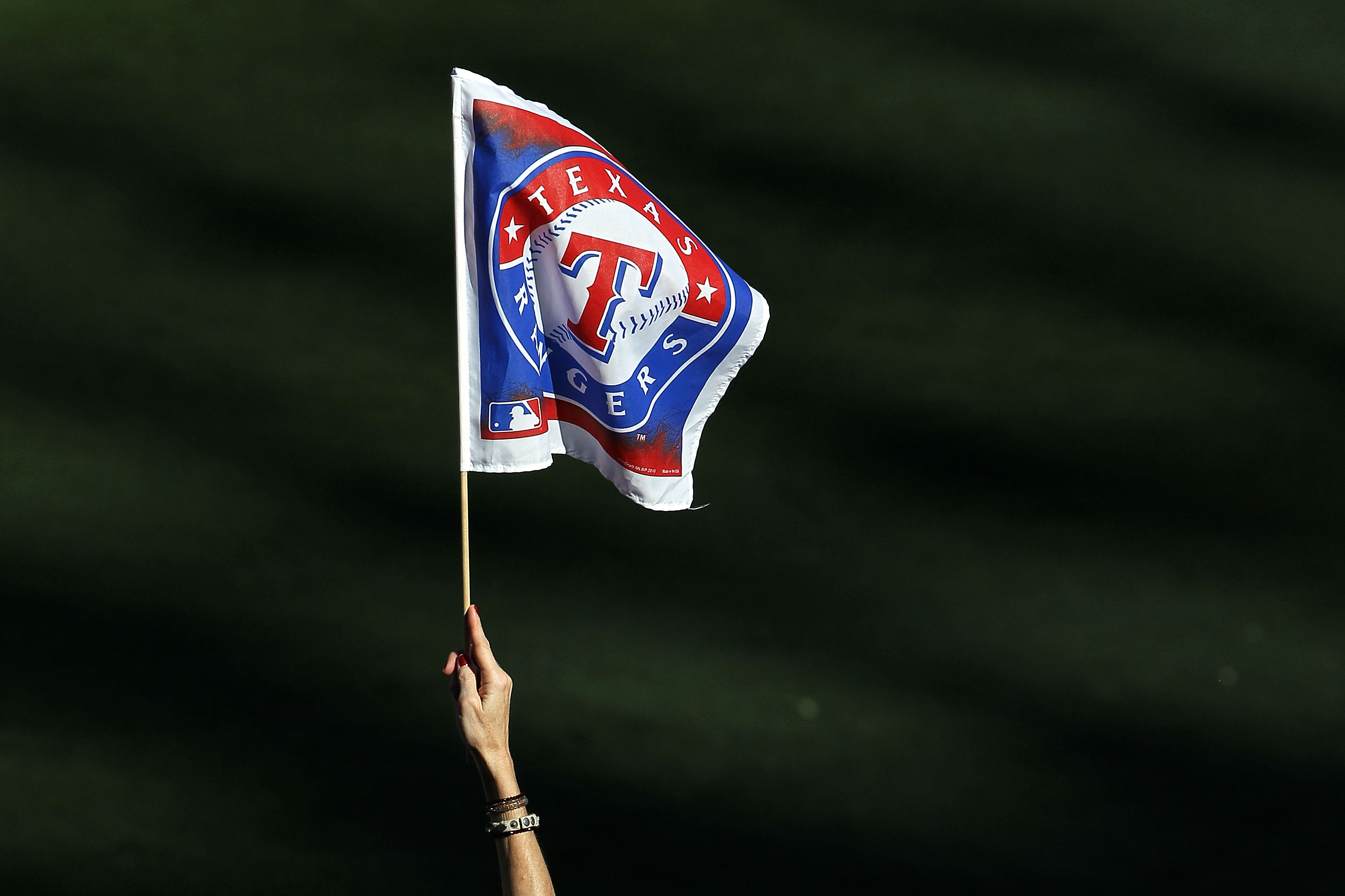 ARLINGTON, TX - OCTOBER 30:  A fan of the Texas Rangers holds up a Rangers' flag against the San Francisco Giants in Game Three of the 2010 MLB World Series at Rangers Ballpark in Arlington on October 30, 2010 in Arlington, Texas.  (Photo by Ronald Martin