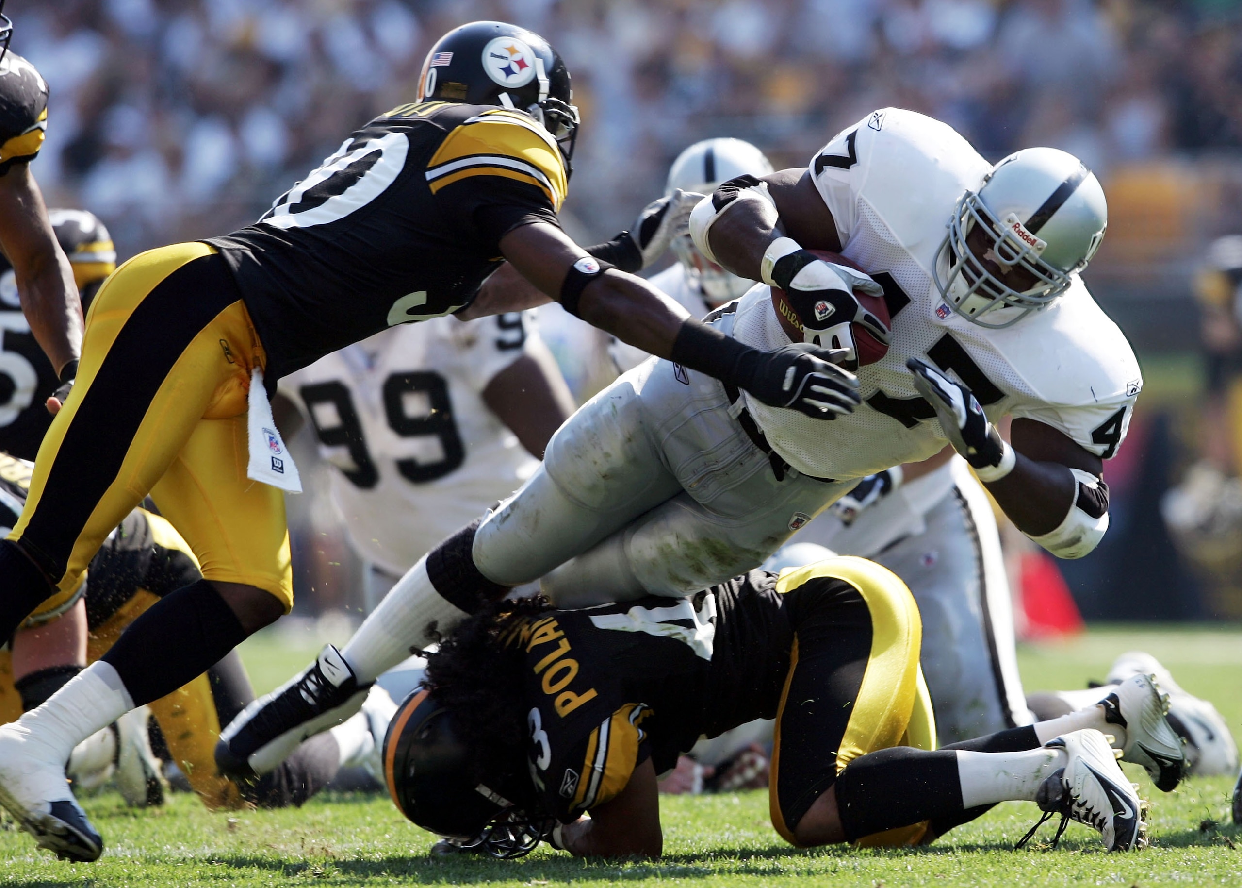 PITTSBURGH - SEPTEMBER 12:  Tyrone Wheatley #47 of the Oakland Raiders runs with the ball while tackled by Chad Scott #30 and Troy Polamalu #43 the Pittsburgh Steelers on September 12, 2004 at Heinz Field in Pittsburgh, Pennsylvania. The Steelers won 24-2