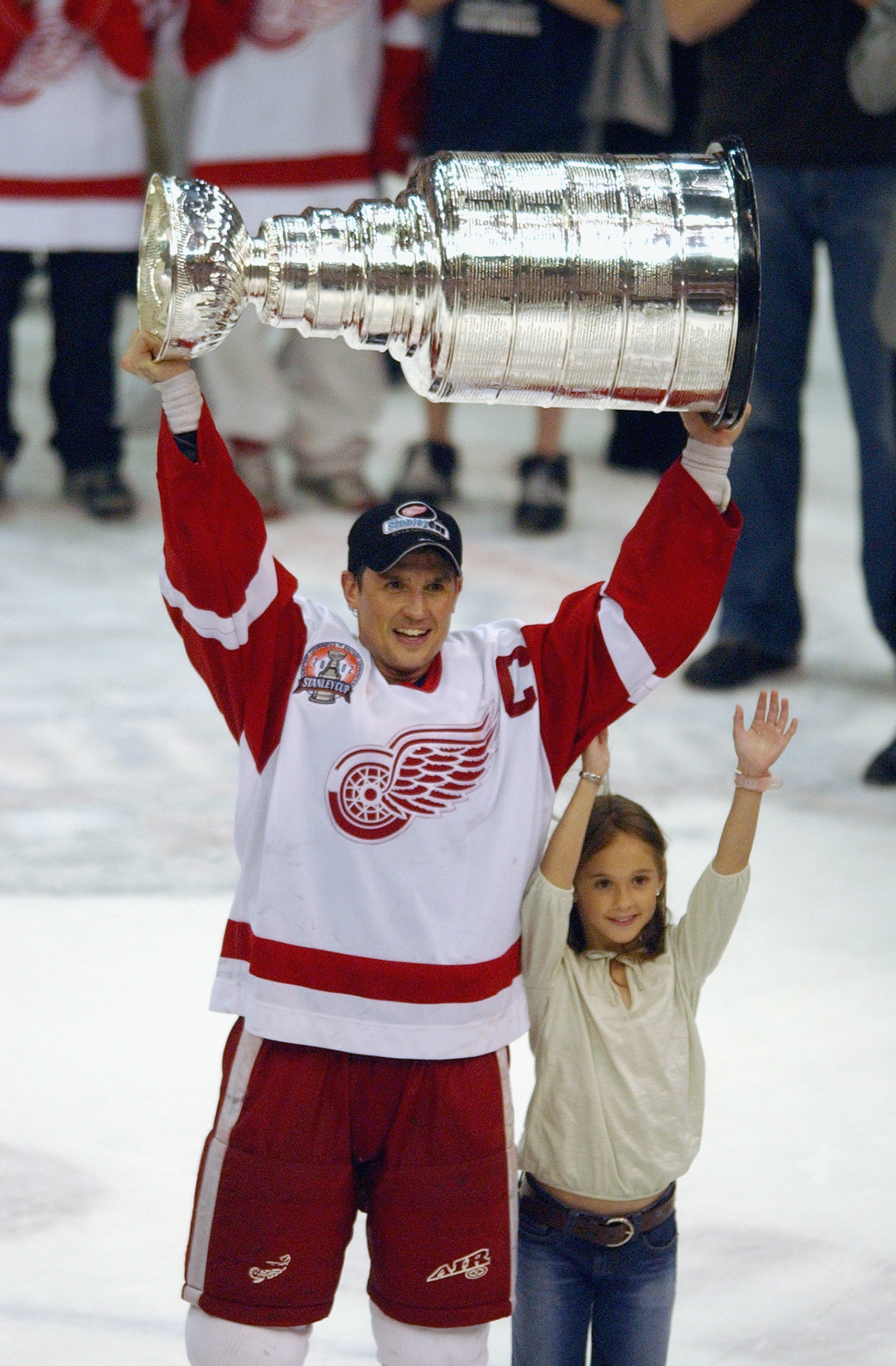 DETROIT, MI - JUNE 13:   Steve Yzerman #19 of the Detroit Red Wings hoists the Stanley Cup next to his daughter Isabella after defeating the Carolina Hurricanes 3-1 in game five of the NHL Stanley Cup Finals on June 13, 2002 at the Joe Louis Arena in Detr
