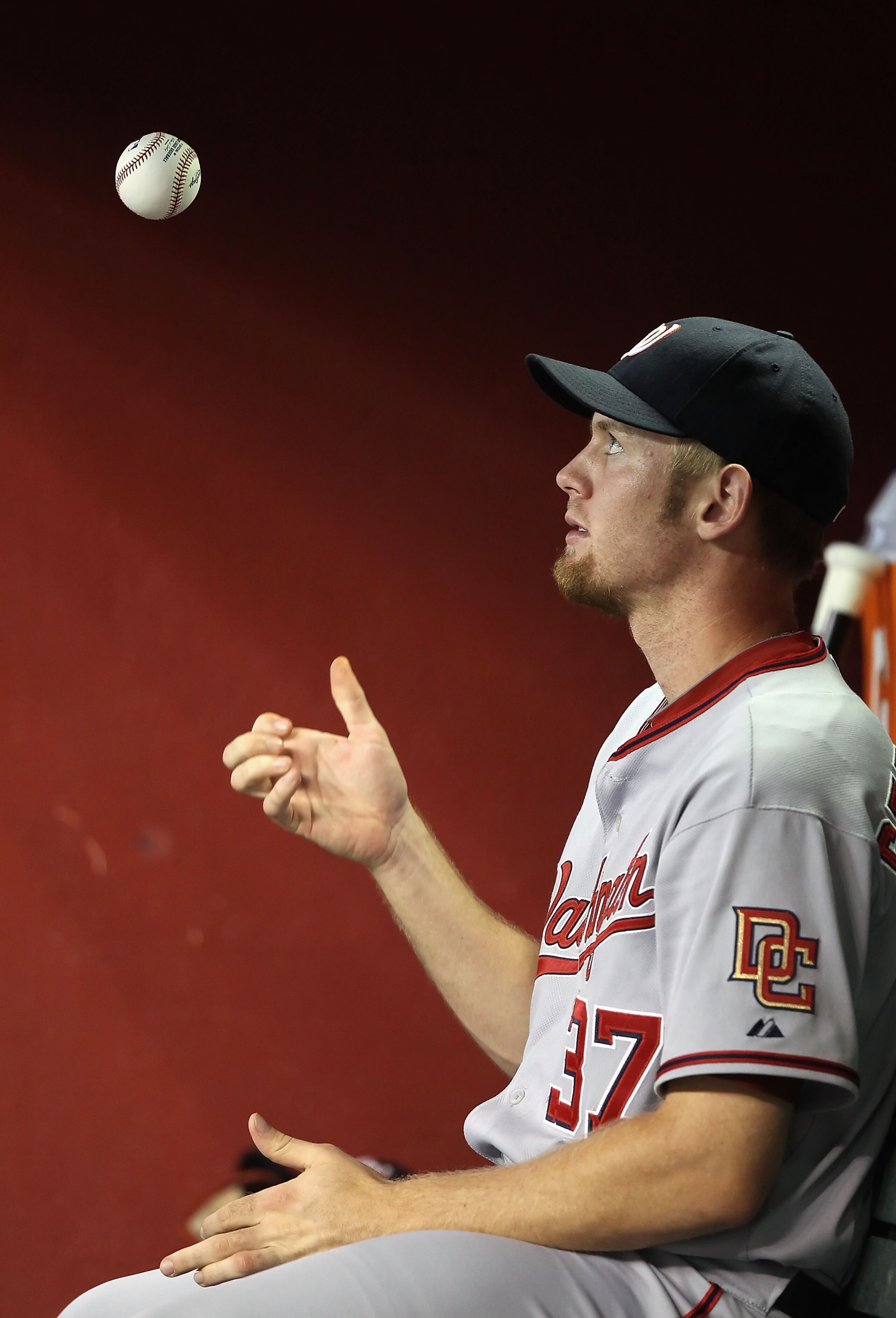 PHOENIX - AUGUST 04:  Pitcher Stephen Strasburg #37 of the Washington Nationals flips a ball as he sits in the dugout during the Major League Baseball game against the Arizona Diamondbacks at Chase Field on August 4, 2010 in Phoenix, Arizona.  (Photo by C