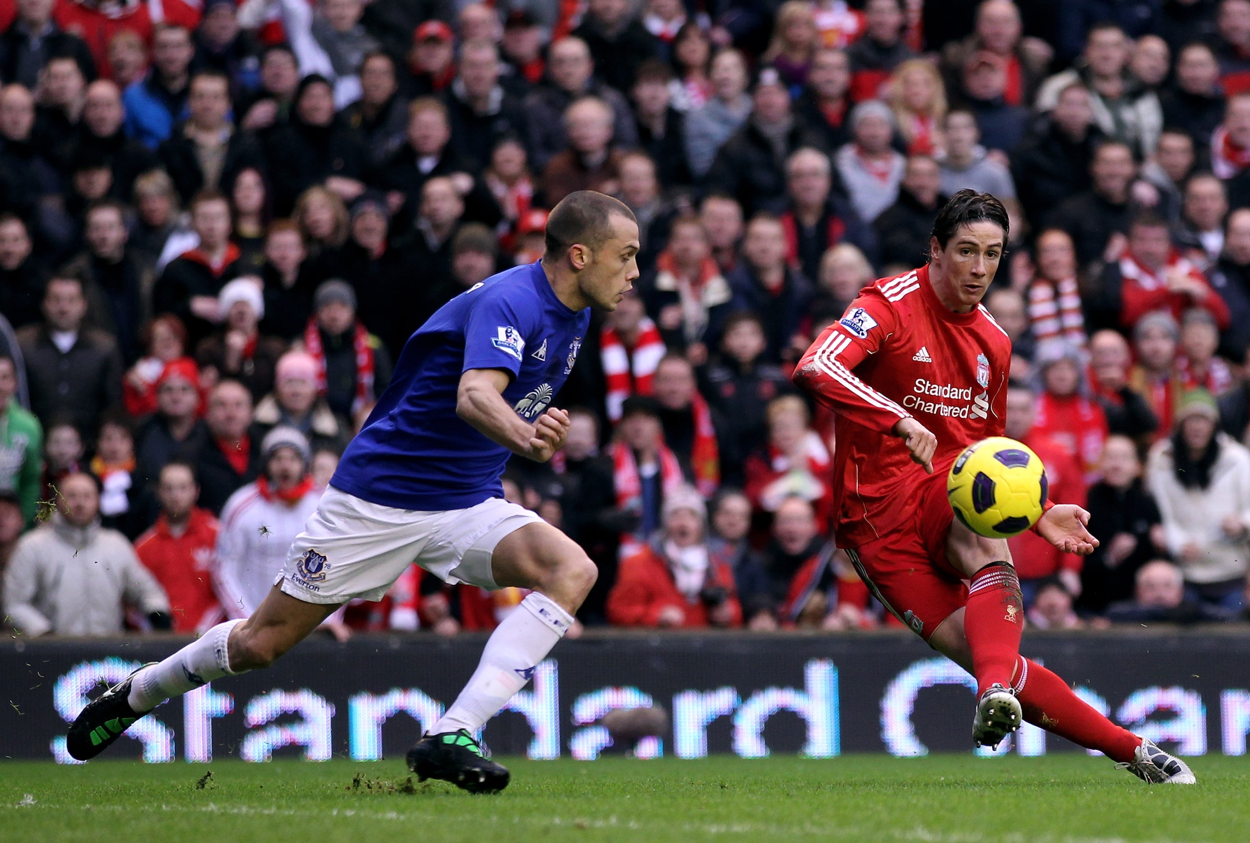 LIVERPOOL, ENGLAND - JANUARY 16:  Fernando Torres of Liverpool shoots past John Heitinga of Everton and subsequently hits the post during the Barclays Premier League match between Liverpool and Everton at Anfield on January 16, 2011 in Liverpool, England.